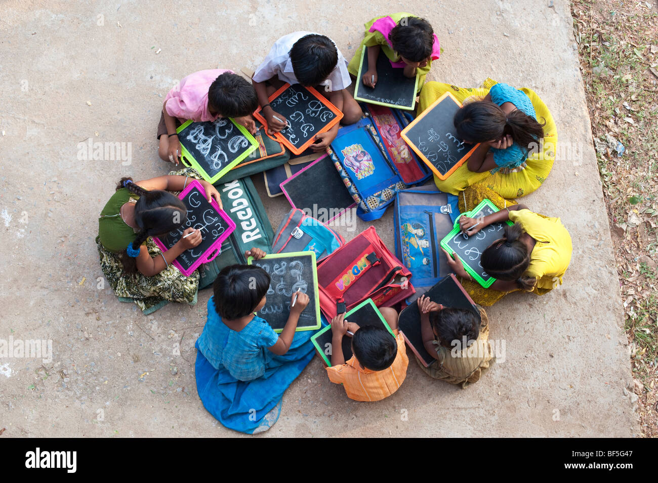 Blick auf Indian School Kinder sitzen außerhalb ihrer Schule schreiben auf der Schiefertafel. Andhra Pradesh, Indien Stockfoto