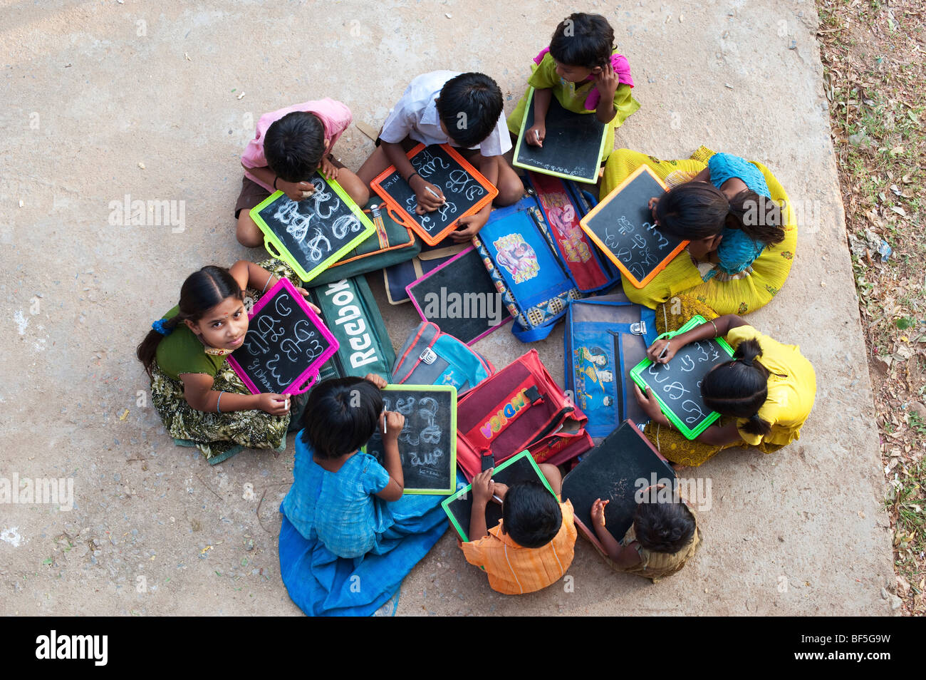 Blick auf Indian School Kinder sitzen außerhalb ihrer Schule schreiben auf der Schiefertafel. Andhra Pradesh, Indien Stockfoto