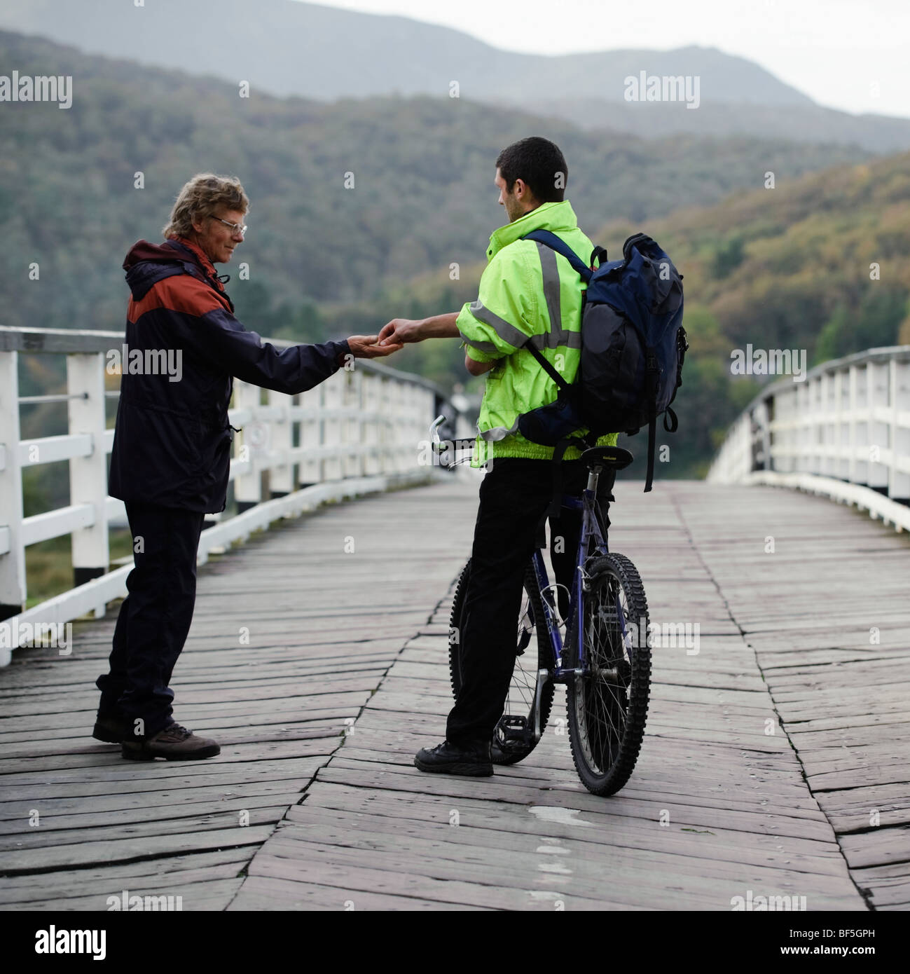 Ein Radfahrer Zahlung den Maut-Keeper, überqueren die alte hölzerne privat im Besitz mautpflichtige Brücke bei Penmaenpool, Mawddach Mündung UK Stockfoto