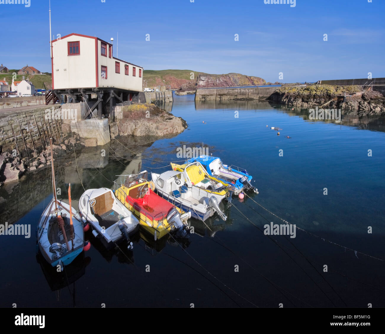 Rettungsstation und eine Reihe von bunten Boote im Hafen von St. Abbs, Schottland Stockfoto