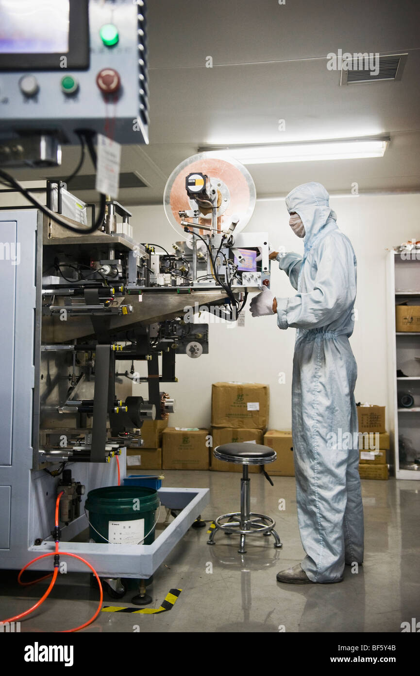 Ein Fabrikarbeiter gekleidet in eine Anti-Kontamination Batteriezellen zu sammeln, wie sie aus der Maschine kommen. Stockfoto