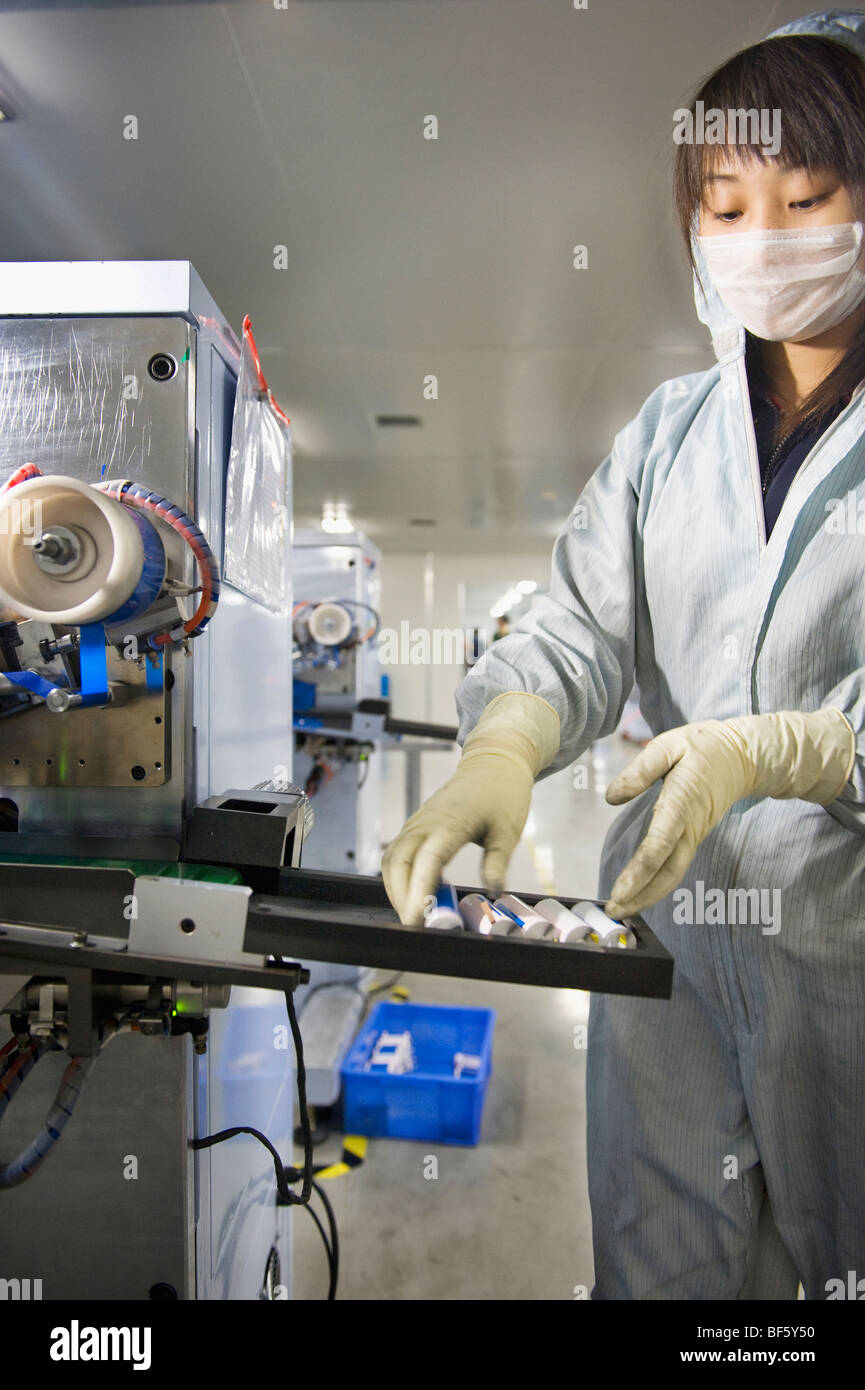 Ein Fabrikarbeiter gekleidet in eine Anti-Kontamination Batteriezellen zu sammeln, wie sie aus der Maschine kommen. Stockfoto
