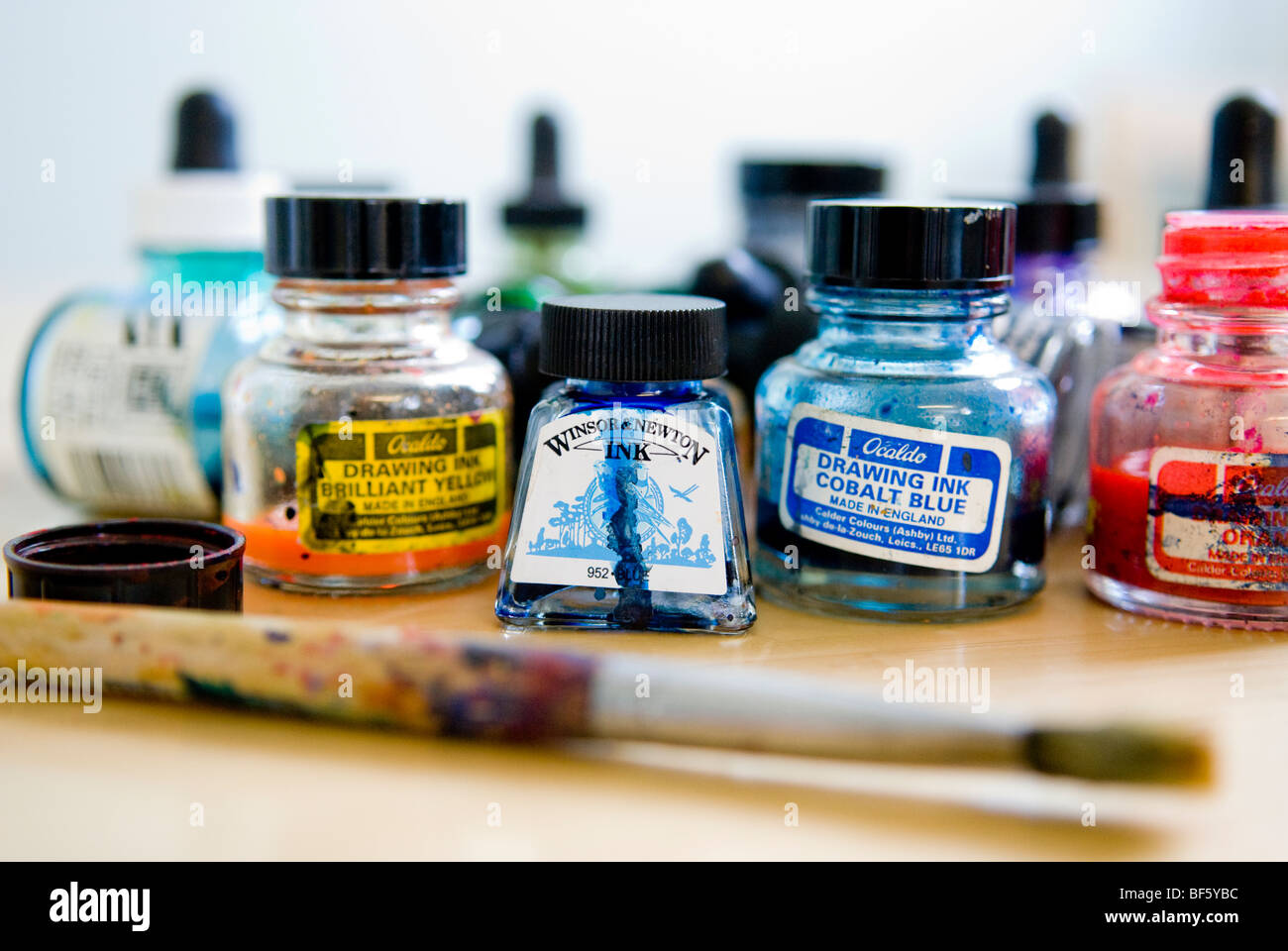 Eine Sammlung von Tinte Töpfe in Flaschen mit einem Pinsel auf einem Tisch. Roter Tinte, blaue Tinte und gelbe Tinte für einen Maler. Stockfoto
