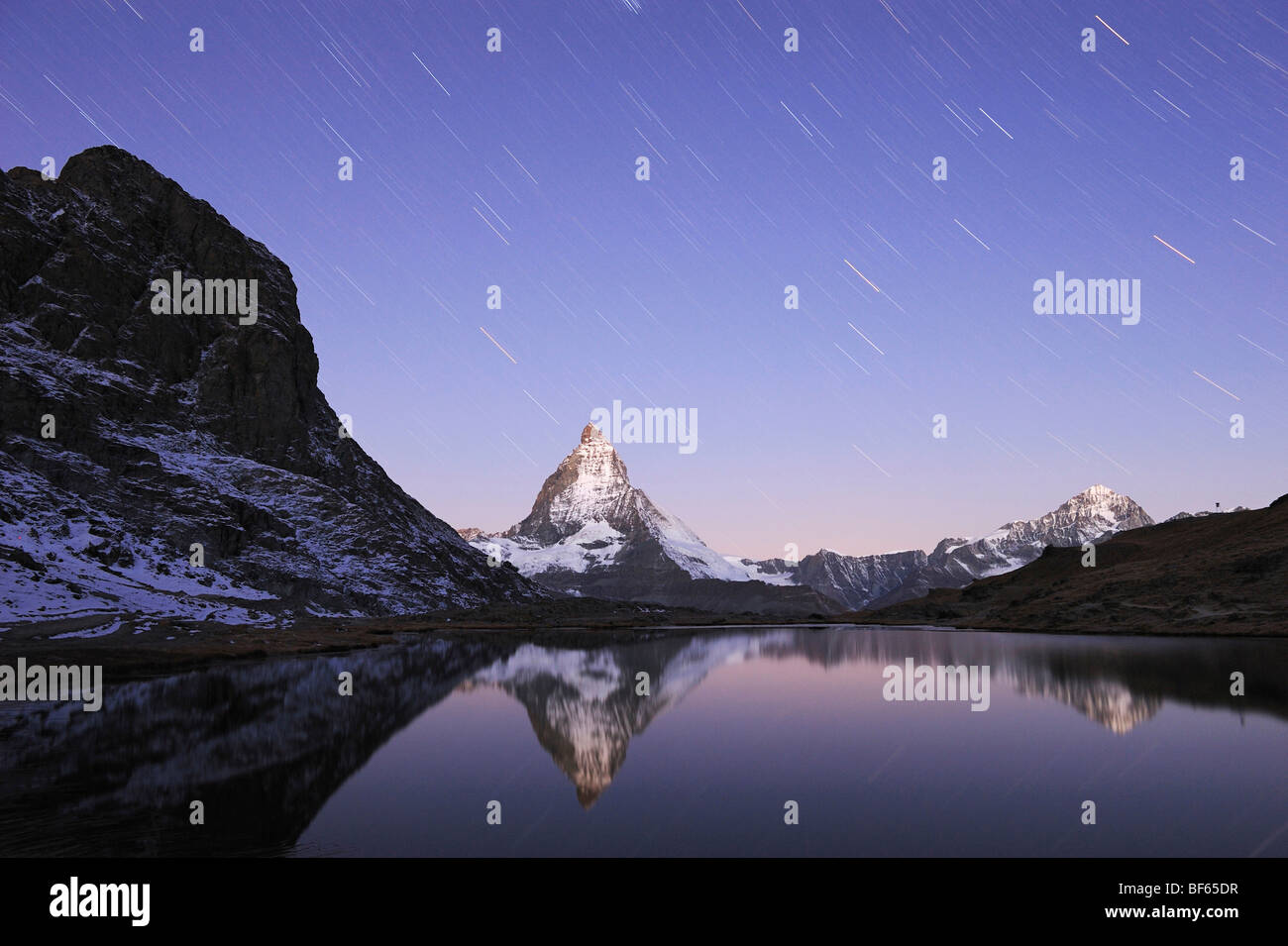 Matterhorn in der Nacht mit Sternspuren im Winter mit Reflexion im Riffelsee, Zermatt, Wallis, Schweiz, Europa Stockfoto