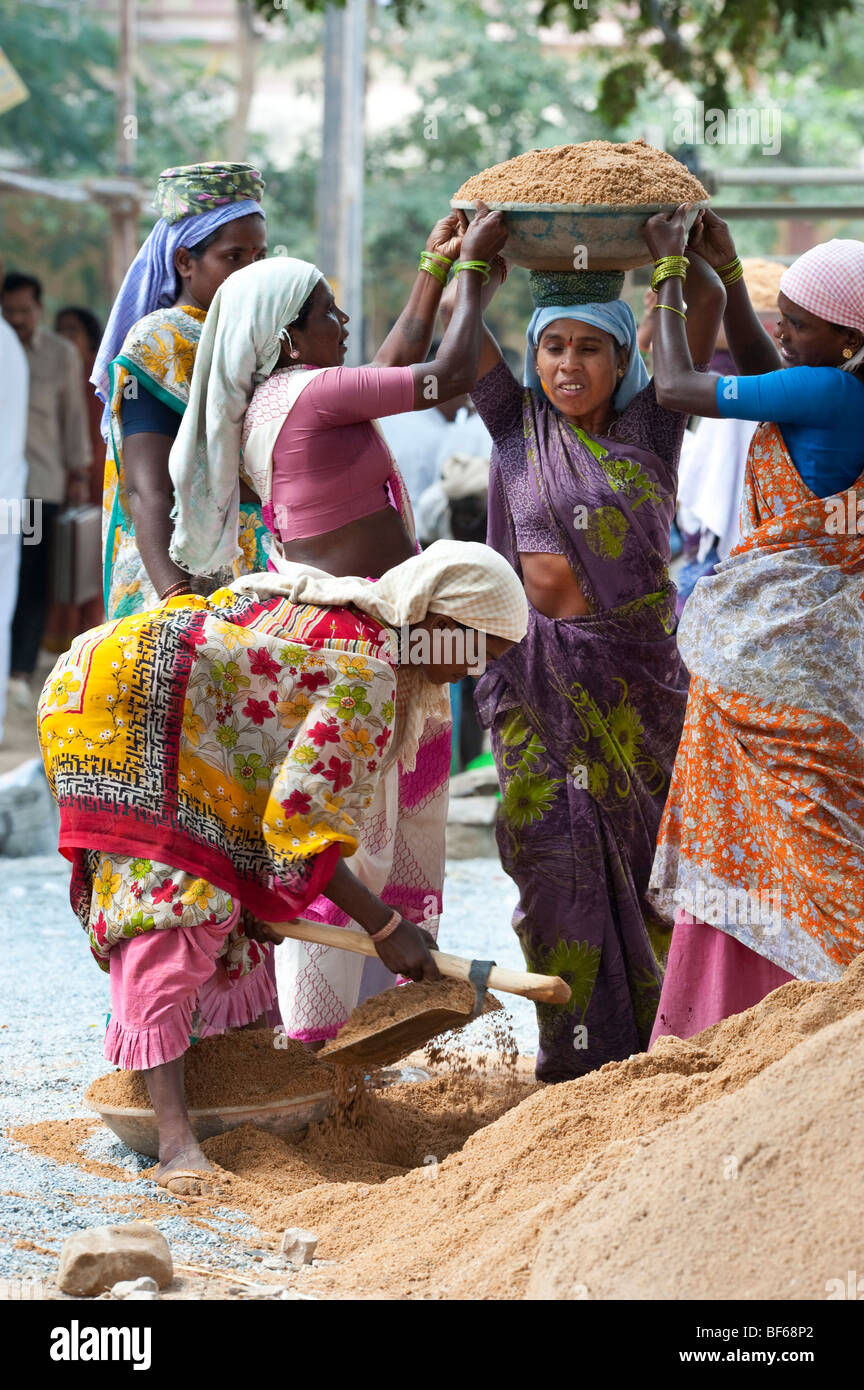 Indische Frau arbeiten auf den Straßen, Heben und Tragen Sand in eine Schüssel geben. Puttaparthi, Andhra Pradesh, Indien Stockfoto