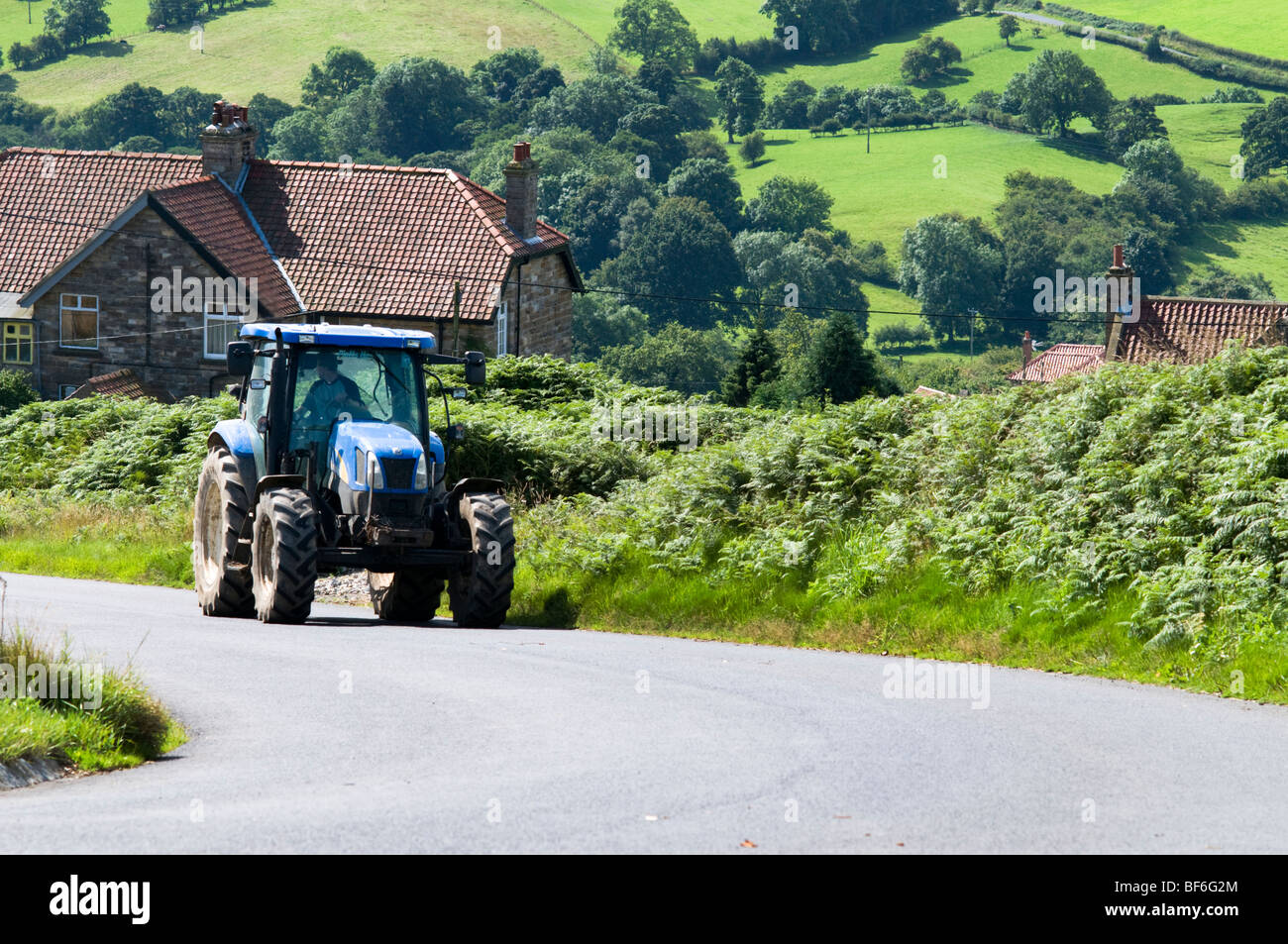 Ein Landwirt Traktor entlang der Landstraße zu fahren, Moors North York, North Yorkshire, UK Stockfoto