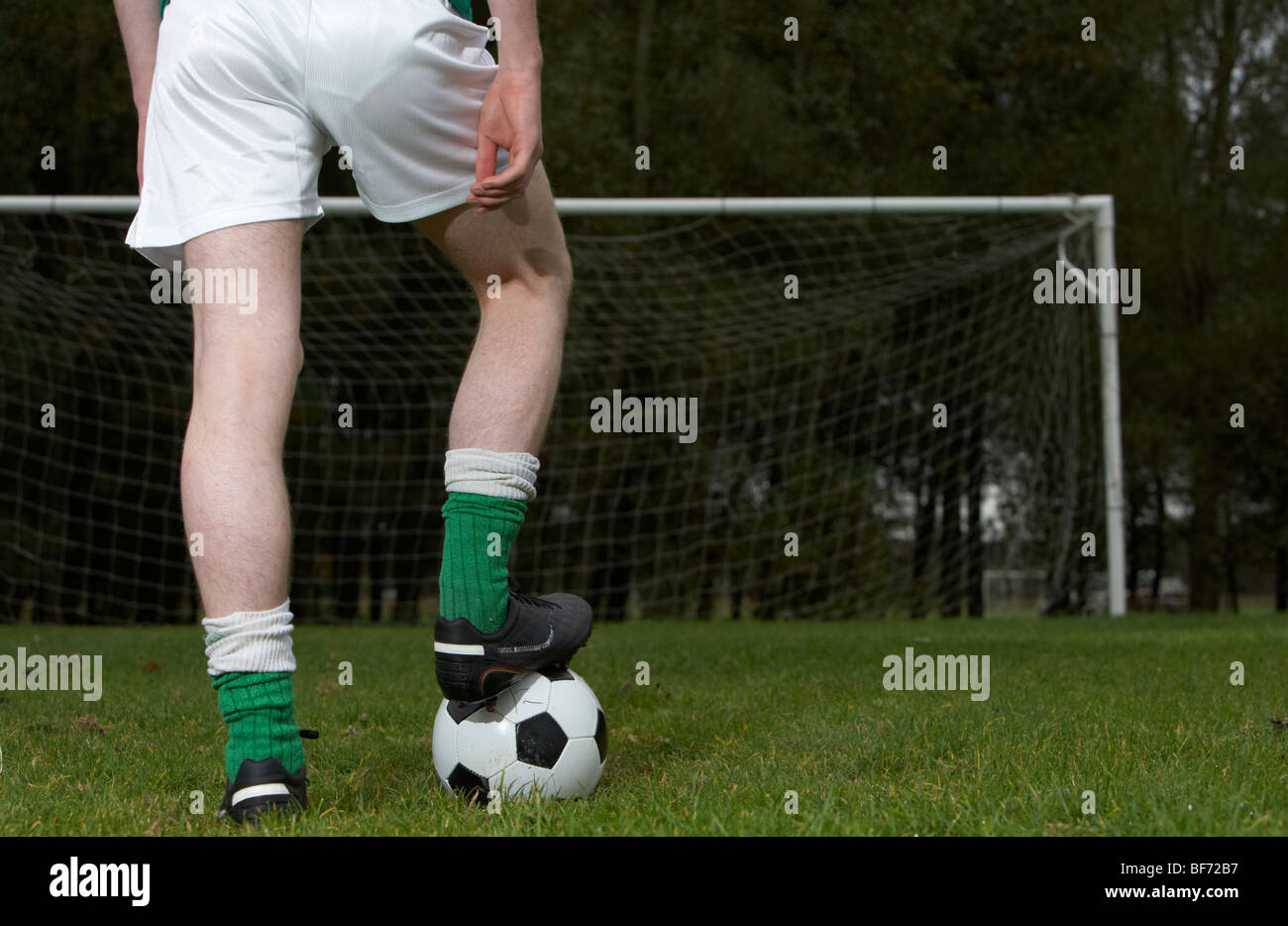 Fußballspieler mit Fuß auf den ball auf die Strafe vor Ort mit Blick auf eine leere Tor stehend Stockfoto