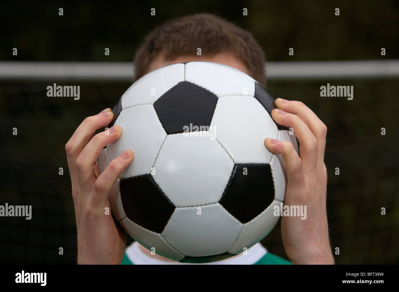 Fußballspieler mit Ball vor seinem Gesicht vor dem Tor Stockfoto