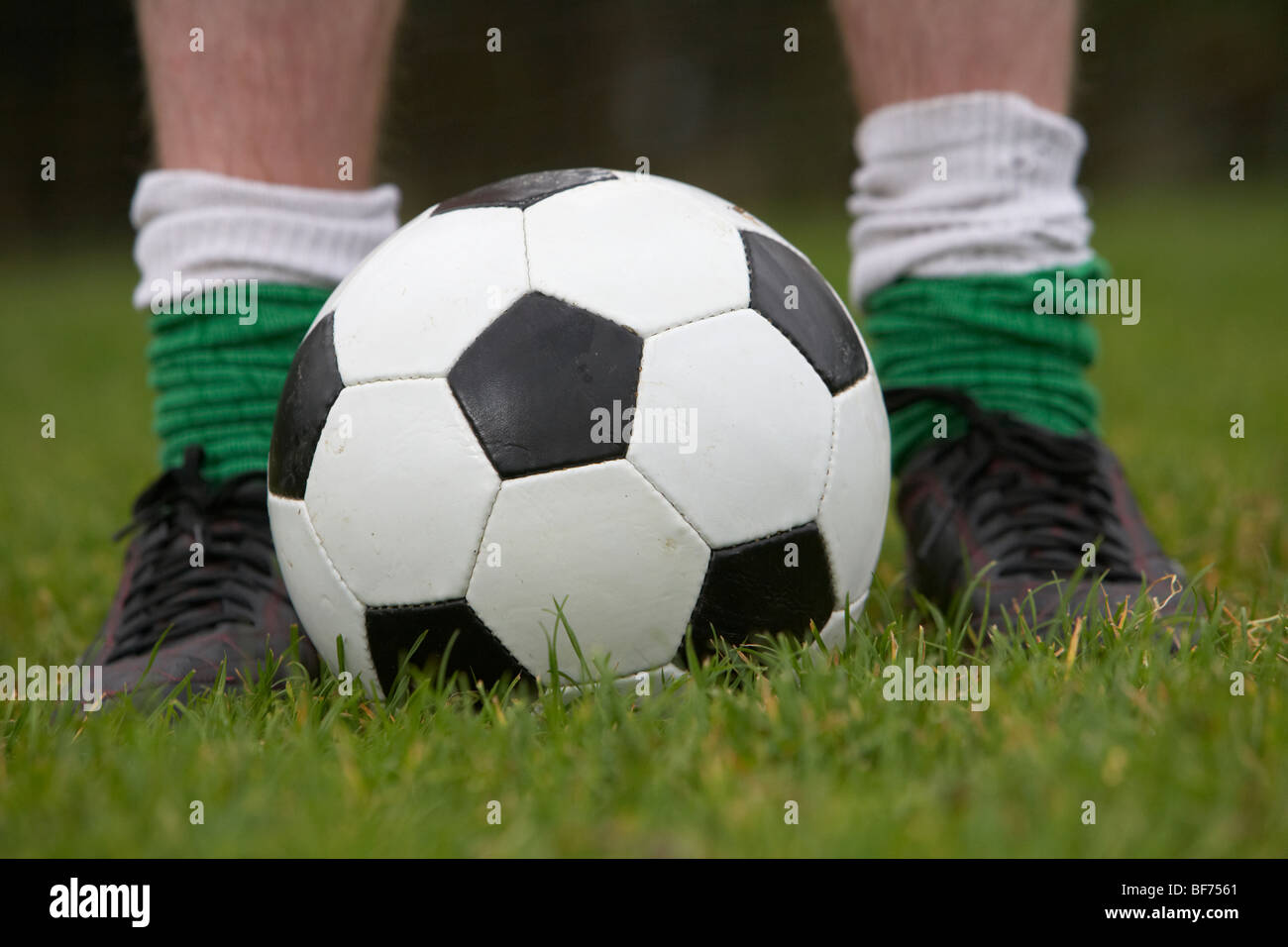 Fußball-Football-Spieler stehen mit Füßen beiderseits eines Balls Stockfoto