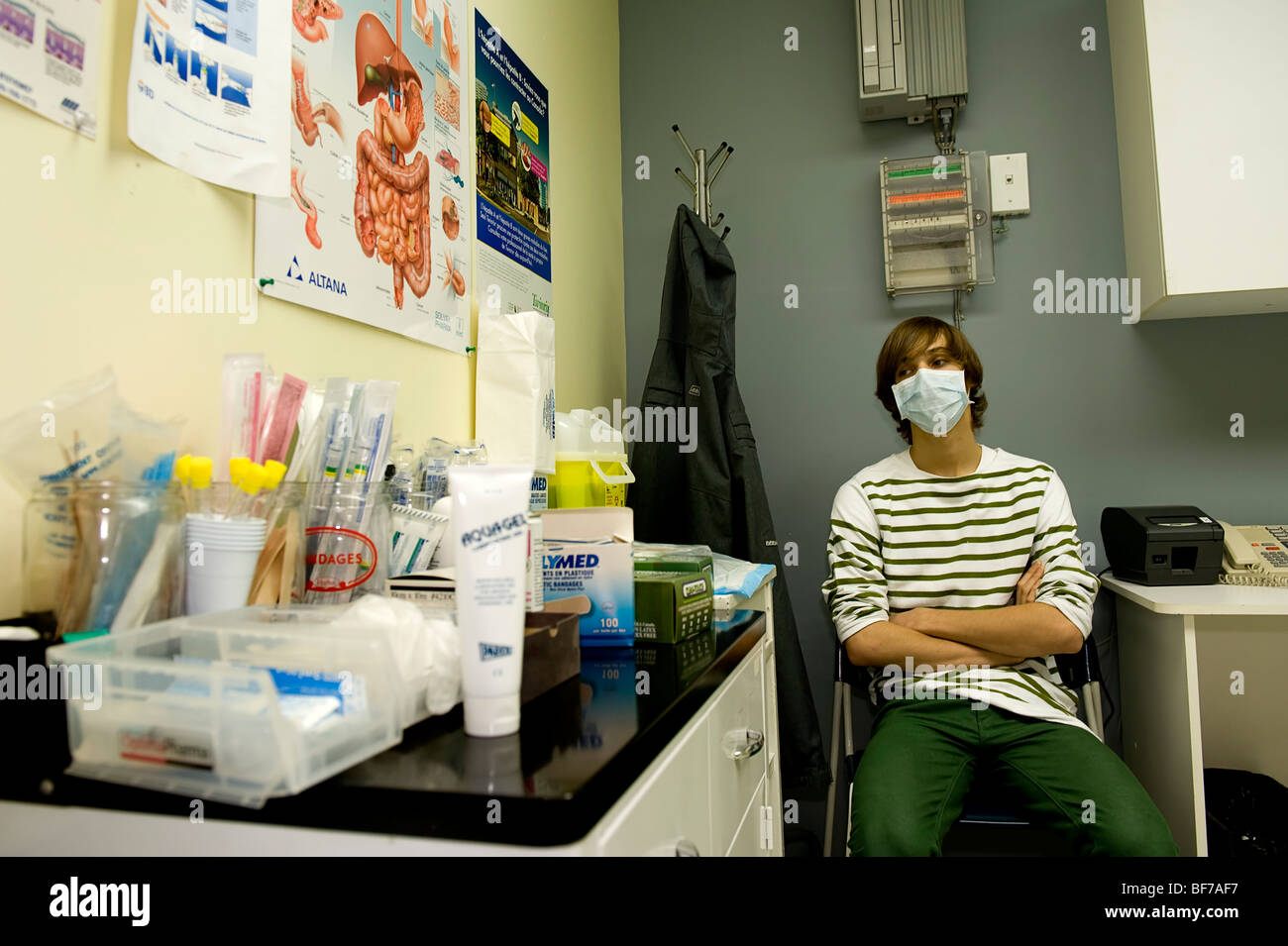 16 Jahre alter Junge mit Maske, die Schweine Grippe H1N1 warten auf den Arzt in einer Klinik zu sehen bekam Stockfoto