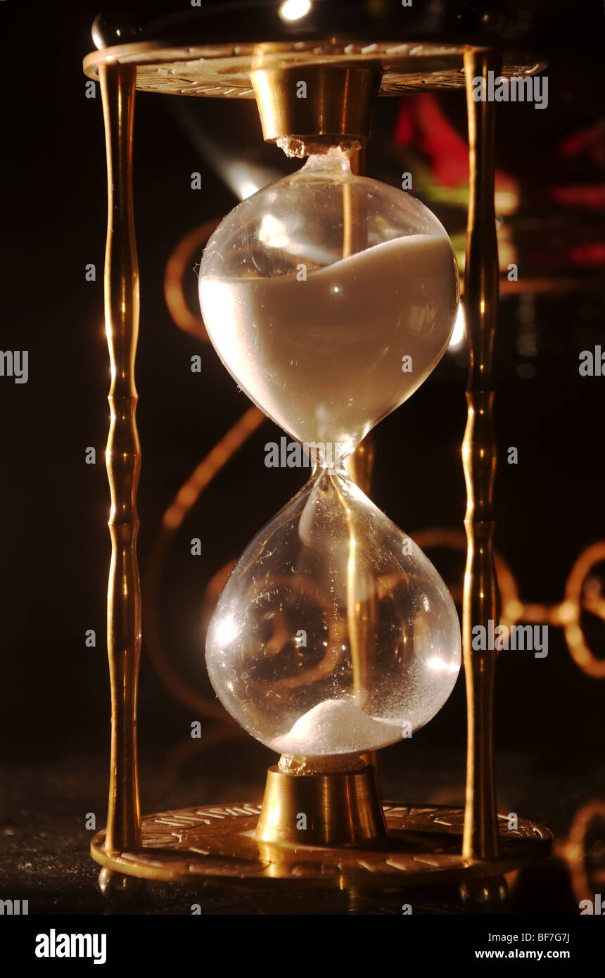 Messing-Sanduhr in einem abgedunkelten Raum Stockfoto