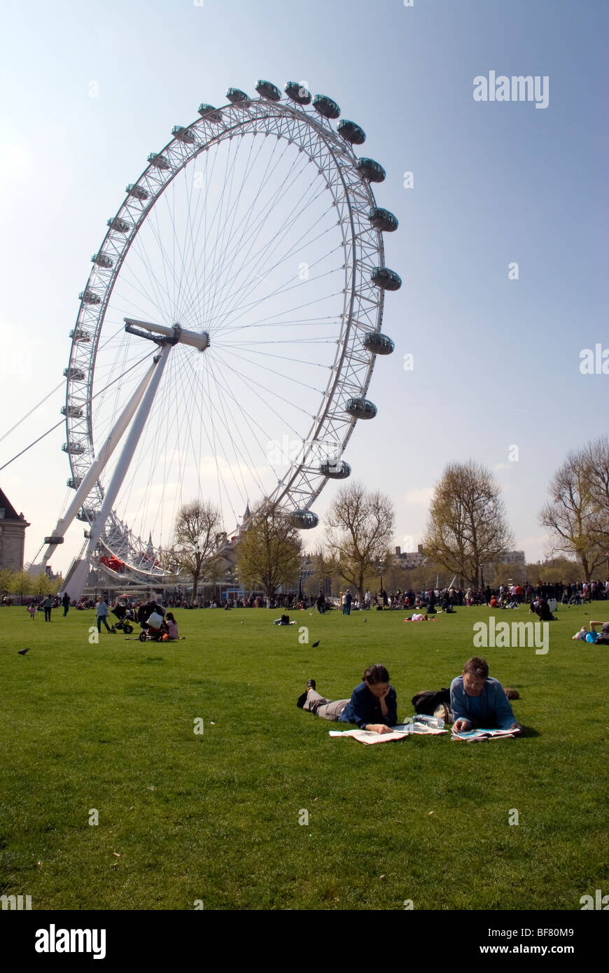 London England UK A paar lesen Sonntagszeitungen in Jubilee Gardens von der Themse und London Eye Stockfoto