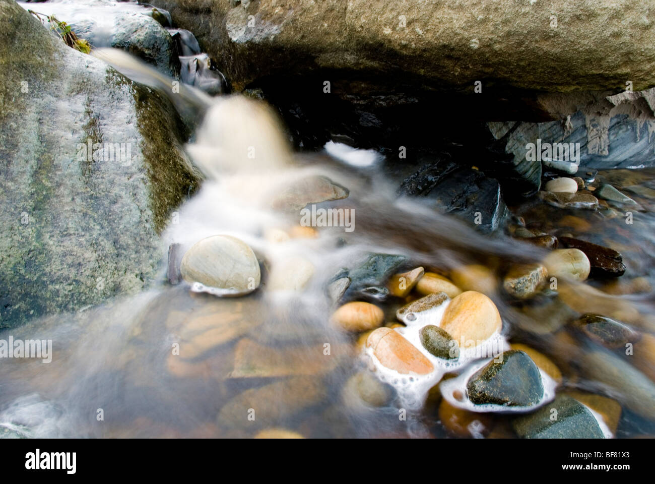 Frisches Wasser läuft über Steinen in einem Strom durch den Ozean Stockfoto