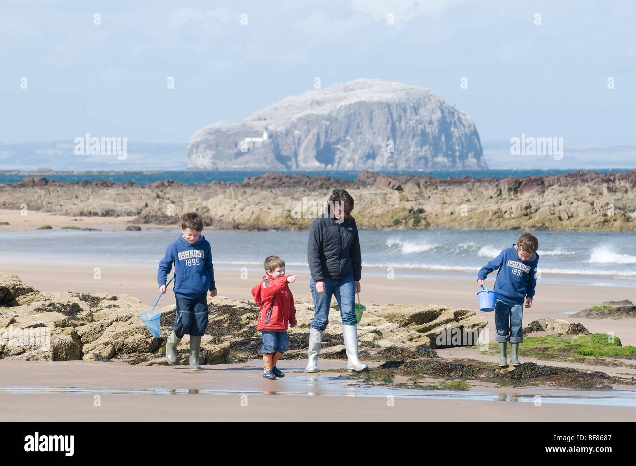 Eine Familie, genießen Sie einen Spaziergang am Strand in East Lothian, Schottland, mit dem Bass Rock im Hintergrund. Stockfoto