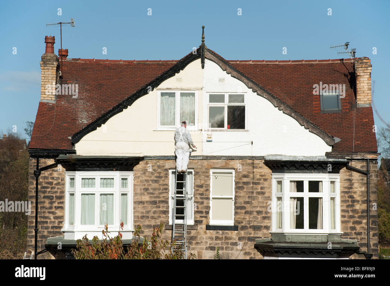 Mann auf einer Leiter, die Malerei eine Doppelhaushälfte Stockfoto