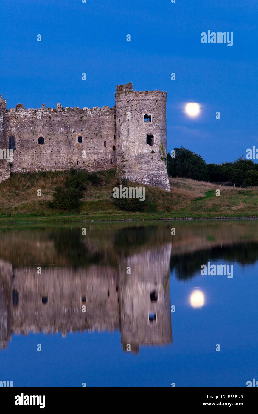 Der Mond, der hinter Carews Castle neben dem Carew-Fluss bei Carews, Pembrokeshire, Wales UK, aufragt Stockfoto