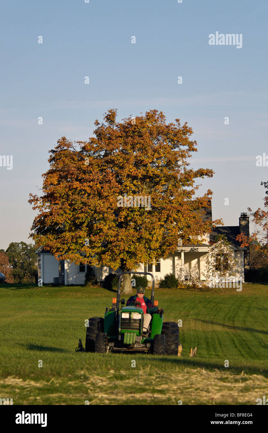 Mann Mähen großen Hof am Landhaus mit John Deere Traktor in Floyd County, Indiana Stockfoto