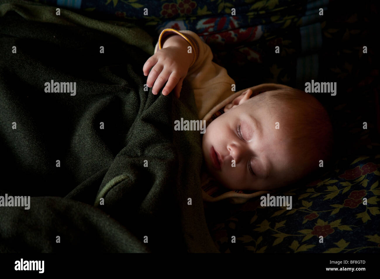 6 Monate altes Babyjungen schlafen in gefleckten Tageslicht, Hampshire, England. Stockfoto