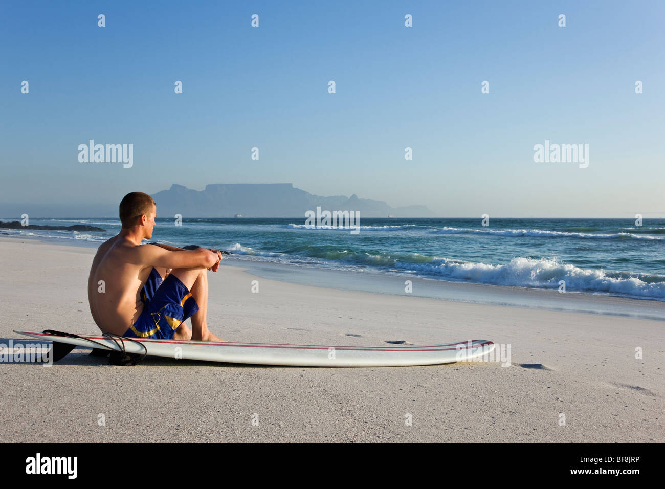 Surfer am Strand von Bloubergstrand mit dem Tafelberg im Hintergrund. Kapstadt-Südafrika Stockfoto