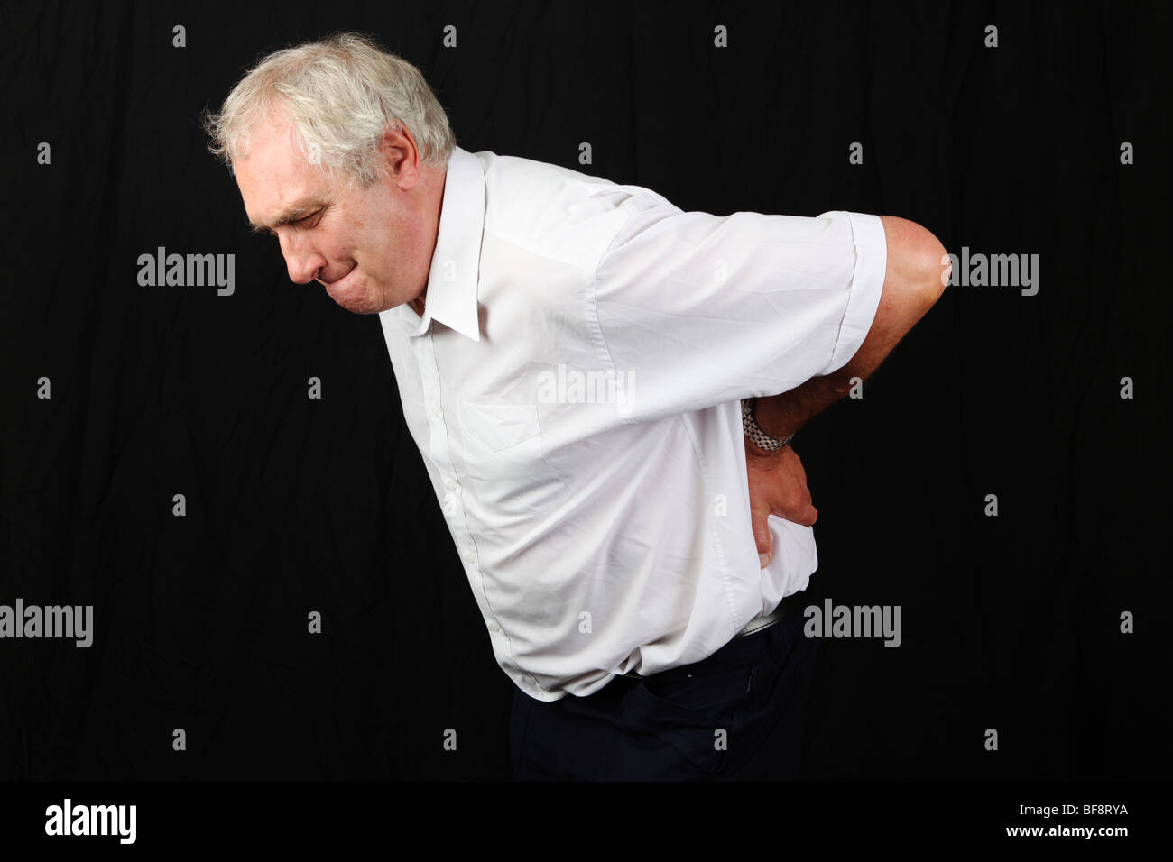 Im späten Mittleren Alter 50er Jahre 60er Jahre Mann Hand in Hand am unteren Rücken leiden mit schweren unteren Rückenschmerzen Bandscheibenvorfall Bandscheibe Problem Stockfoto
