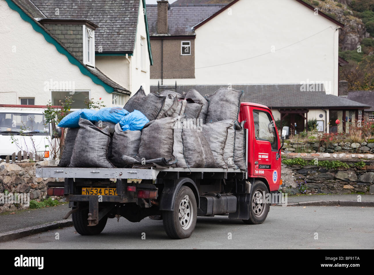 Kohlenhändler an einem Haus mit Säcken des Kraftstoffs auf einem Tieflader auf der Straße. Wales, Großbritannien, Großbritannien Stockfoto