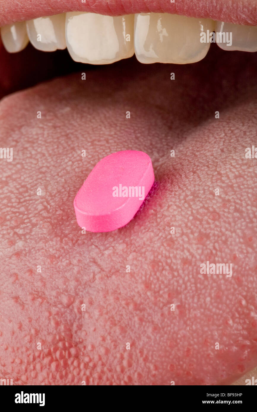 Eine hellere rosa Pille sitzt auf einem menschlichen weiblichen Zunge Stockfoto