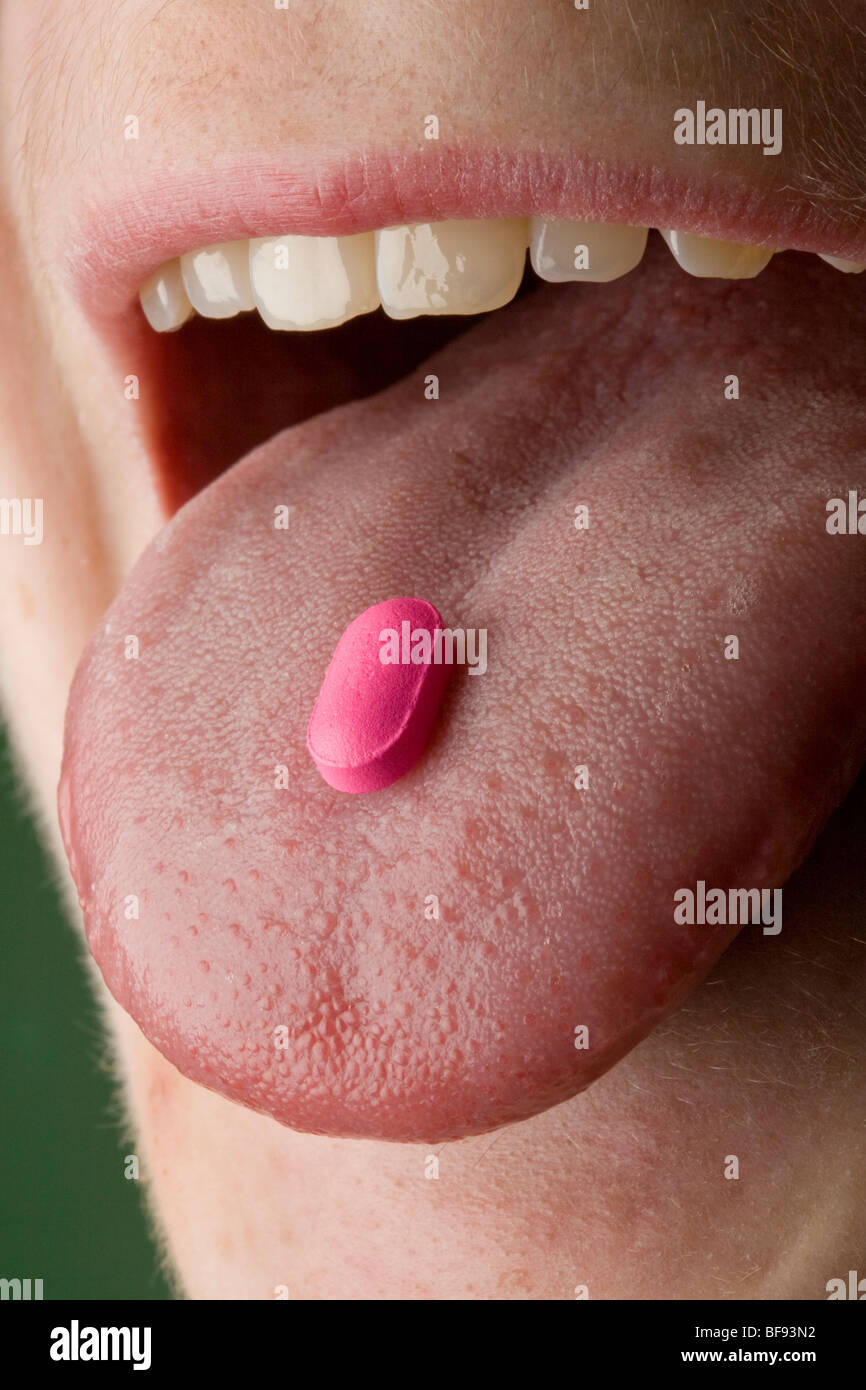 Eine hellere rosa Pille sitzt auf einem menschlichen weiblichen Zunge Stockfoto