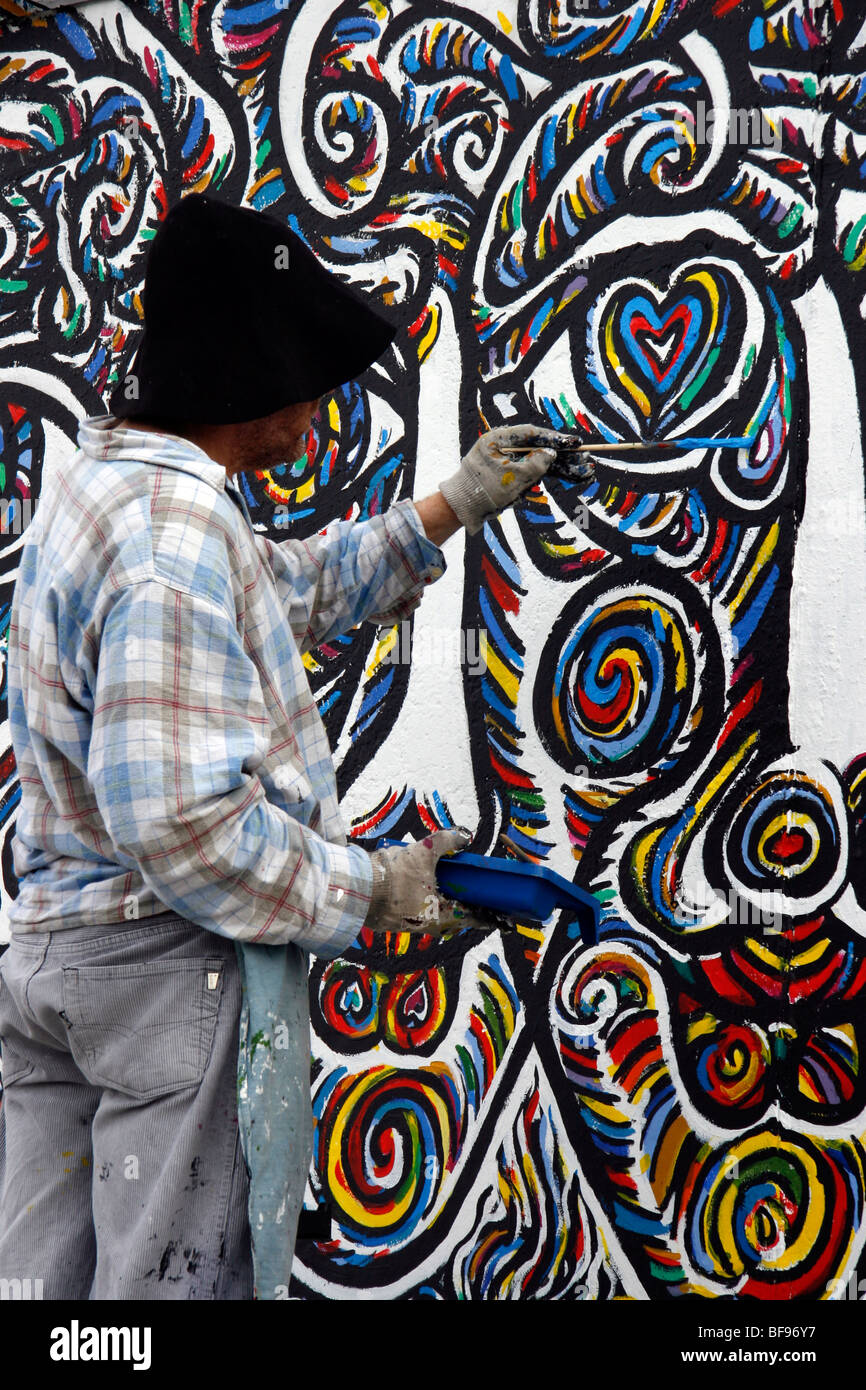 Ein Künstler malt die Berliner Mauer an der East Side Gallery, einem 1,3 km langen Abschnitt der Mauer nahe dem Zentrum von Berlin Stockfoto