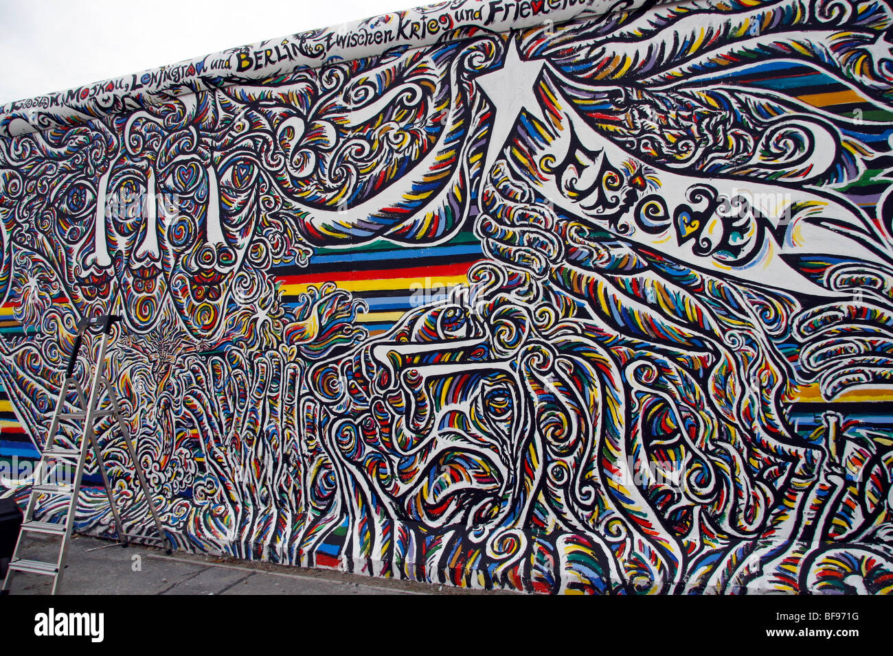 Ein Künstler malt die Berliner Mauer an der East Side Gallery, einem 1,3 km langen Abschnitt der Mauer nahe dem Zentrum von Berlin Stockfoto