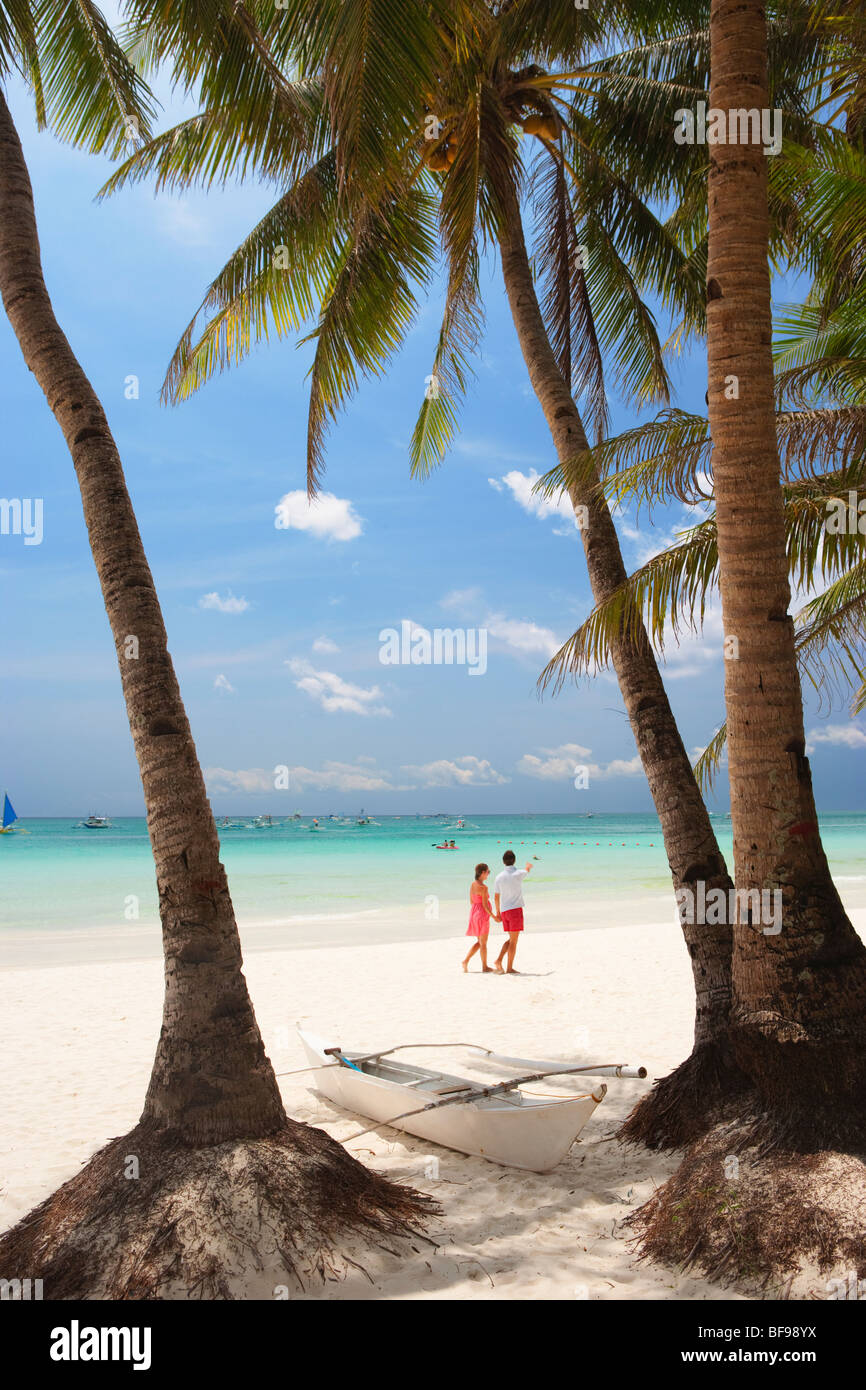 Weißes Boot zwischen zwei Palmen Bäume paar Walkng Strand Boracay; Die Visayas; Philippinen. Stockfoto