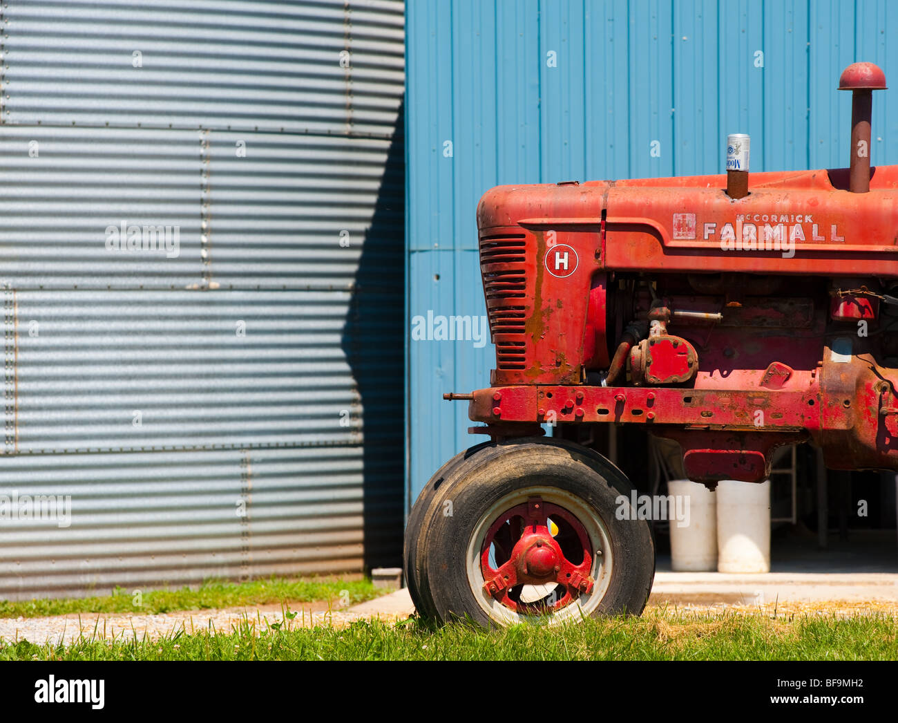 roter Traktor in von Getreidesilos Stockfoto