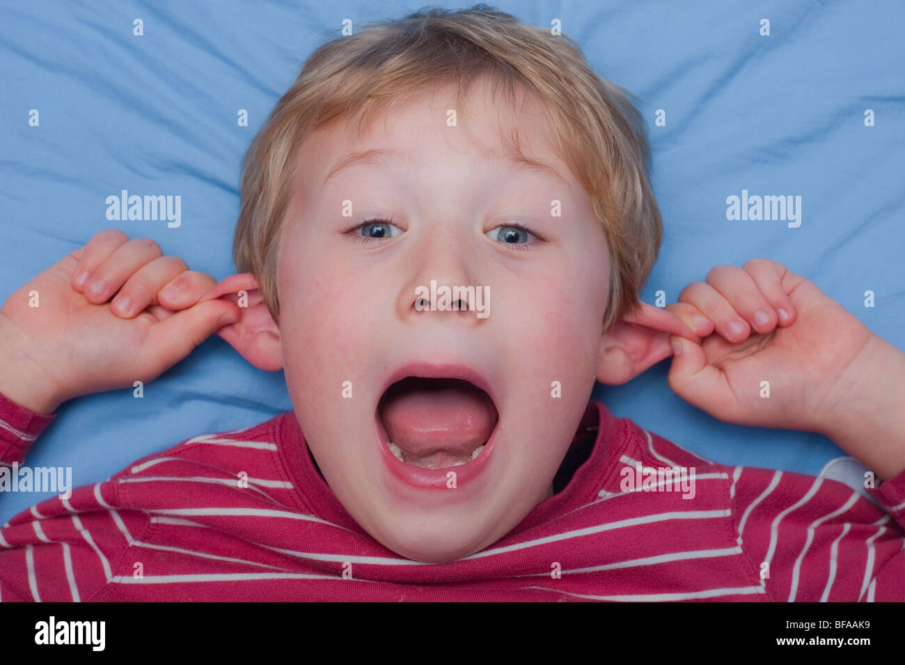 Ein Model Release Bild eines sechsjährigen Jungen ziehen ein dummes Gesicht drinnen im Vereinigten Königreich Stockfoto