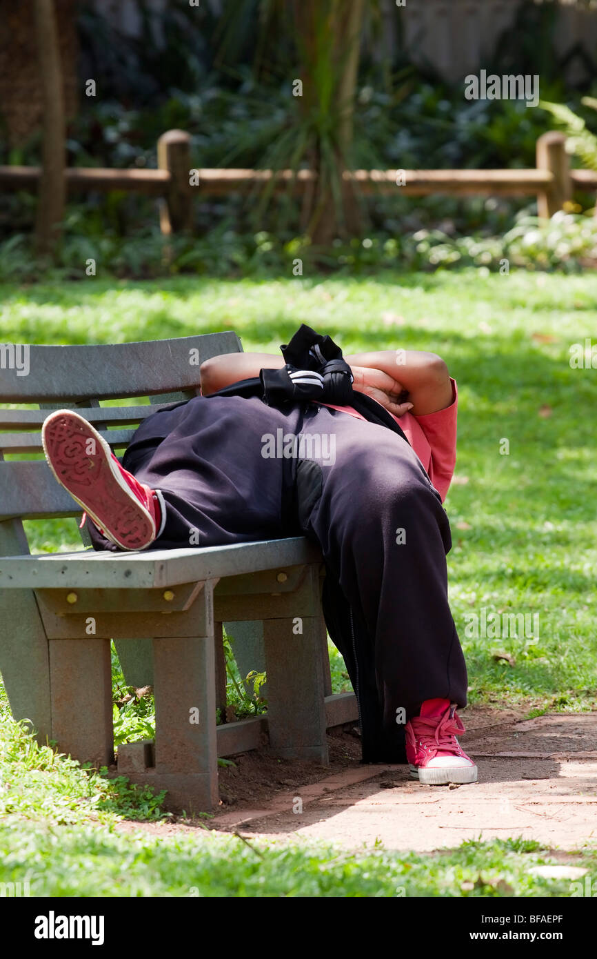 Mann auf Bank, liegend ausruhen von einem Spaziergang durch den park Stockfoto