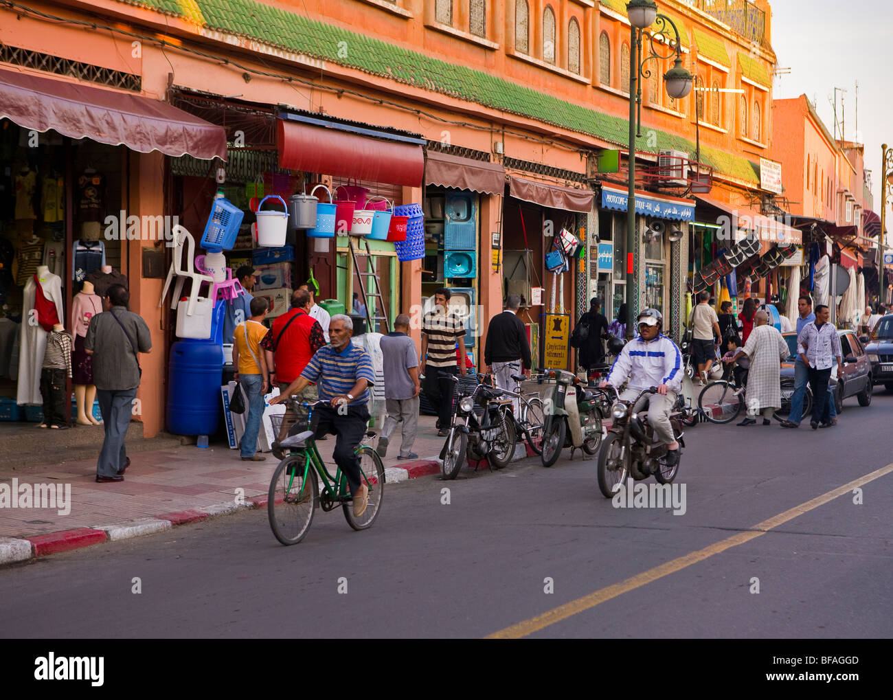 Marrakesch, Marokko - Menschen und Roller und Geschäfte auf Fatima Zohra Street. Stockfoto