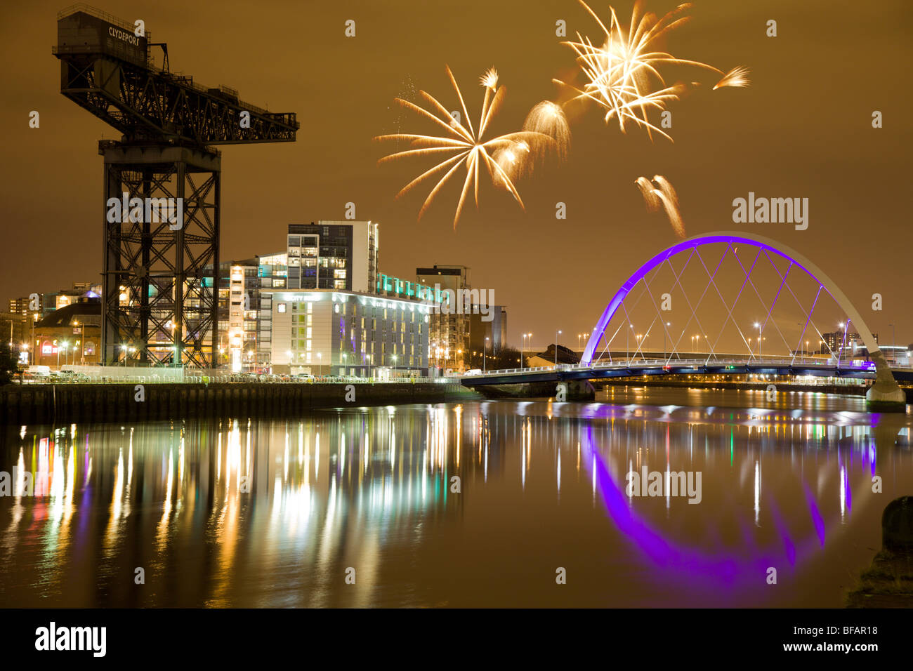 Night Time-Image des Clyde Arc (Squinty Brücke) mit Finnieston Crane mit Feuerwerk im Hintergrund Stockfoto