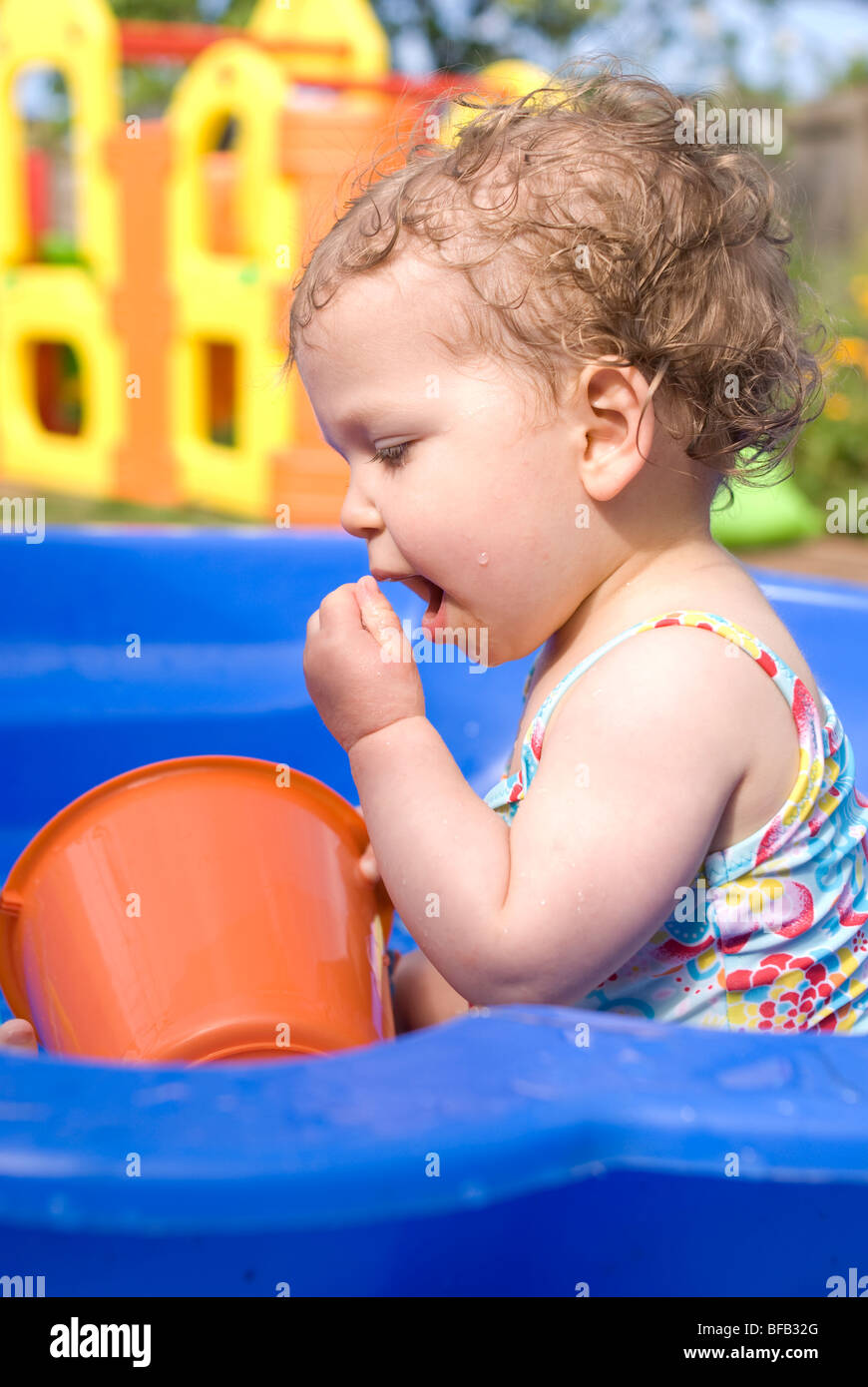 Baby im Planschbecken draußen spielen. Stockfoto