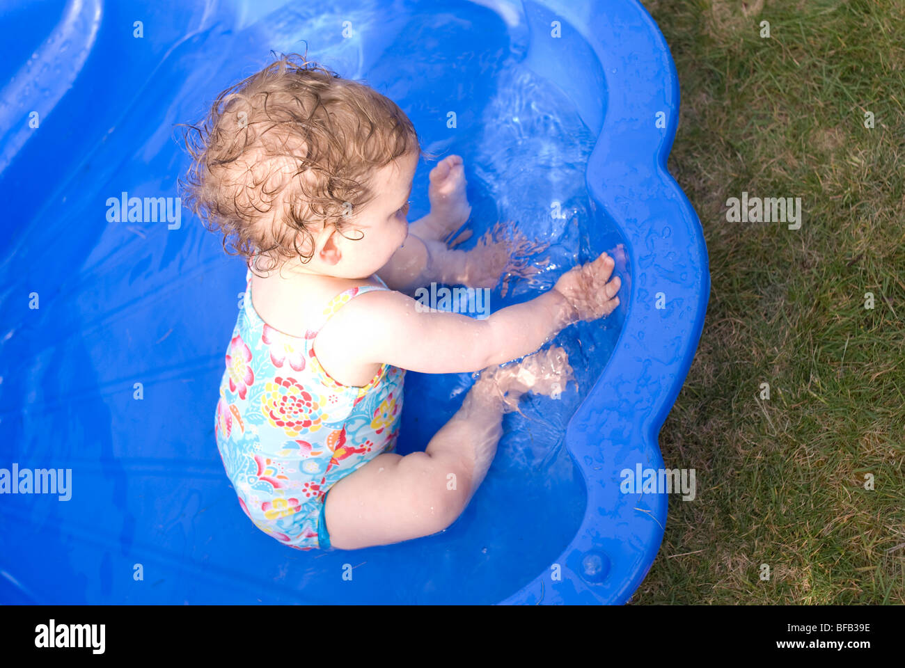 Baby mit Wasser in einem Planschbecken spielen. Stockfoto