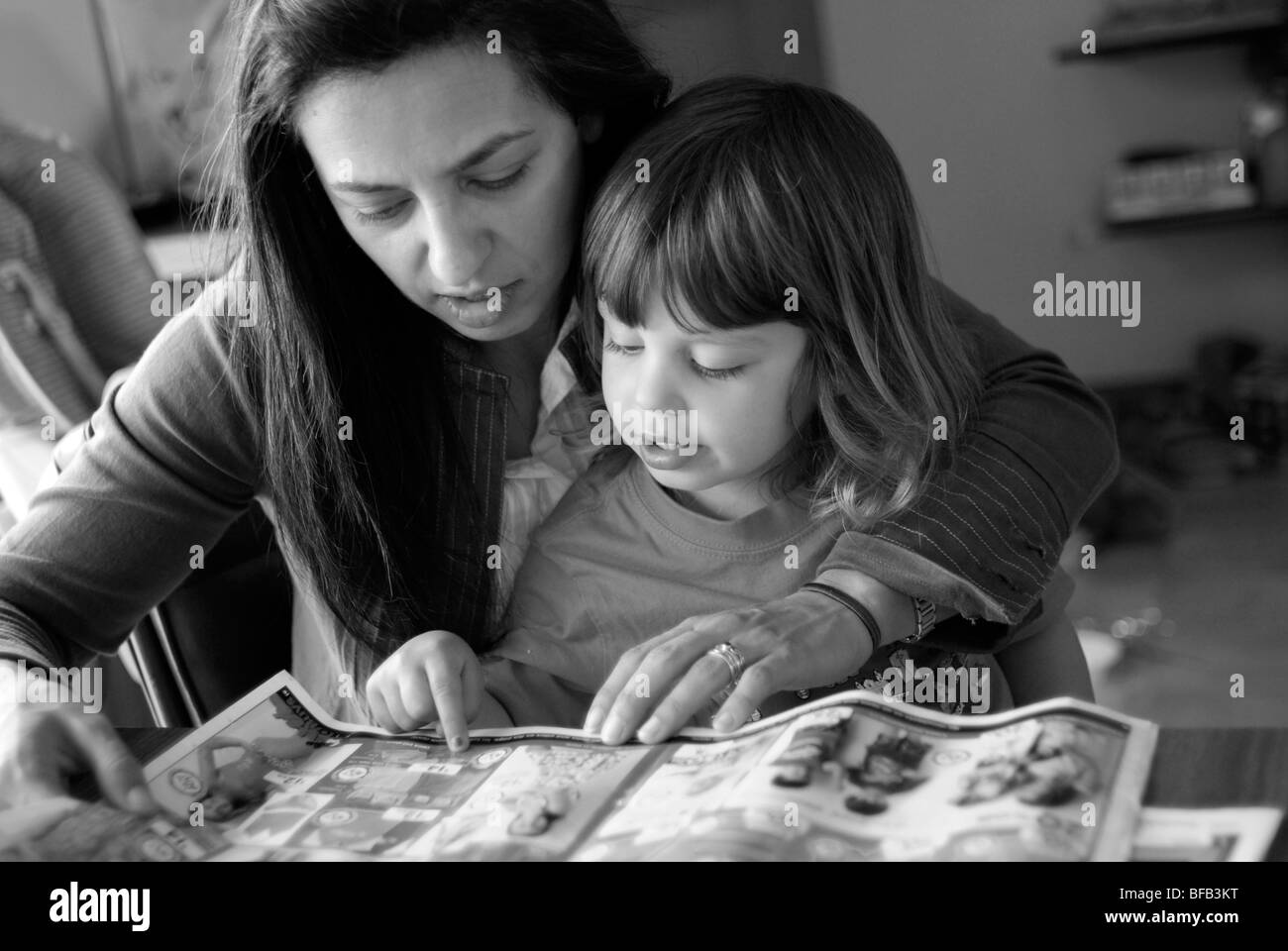 Mutter und Tochter, drei Jahre alt, suchen in Broschüren zusammen einkaufen. Stockfoto
