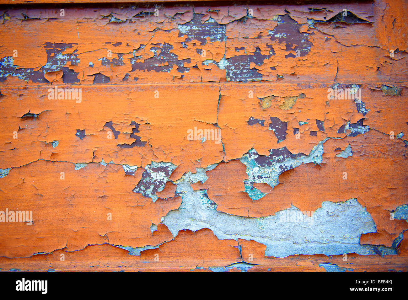 Nahaufnahme der abblätternden orangen Farbe an einer Wand Stockfoto
