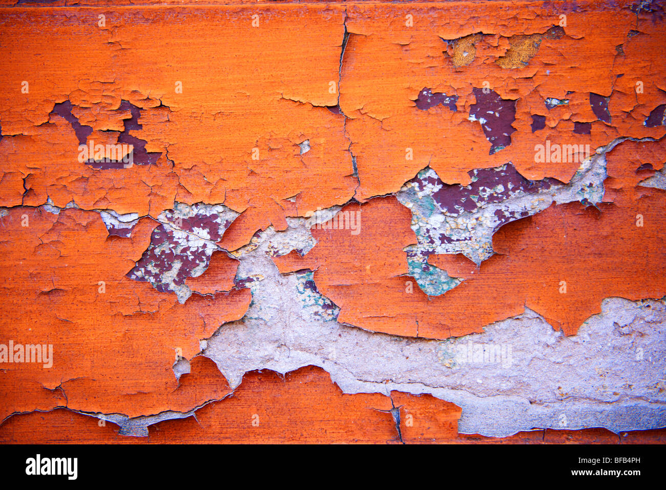 Nahaufnahme der abblätternden orangen Farbe an einer Wand Stockfoto