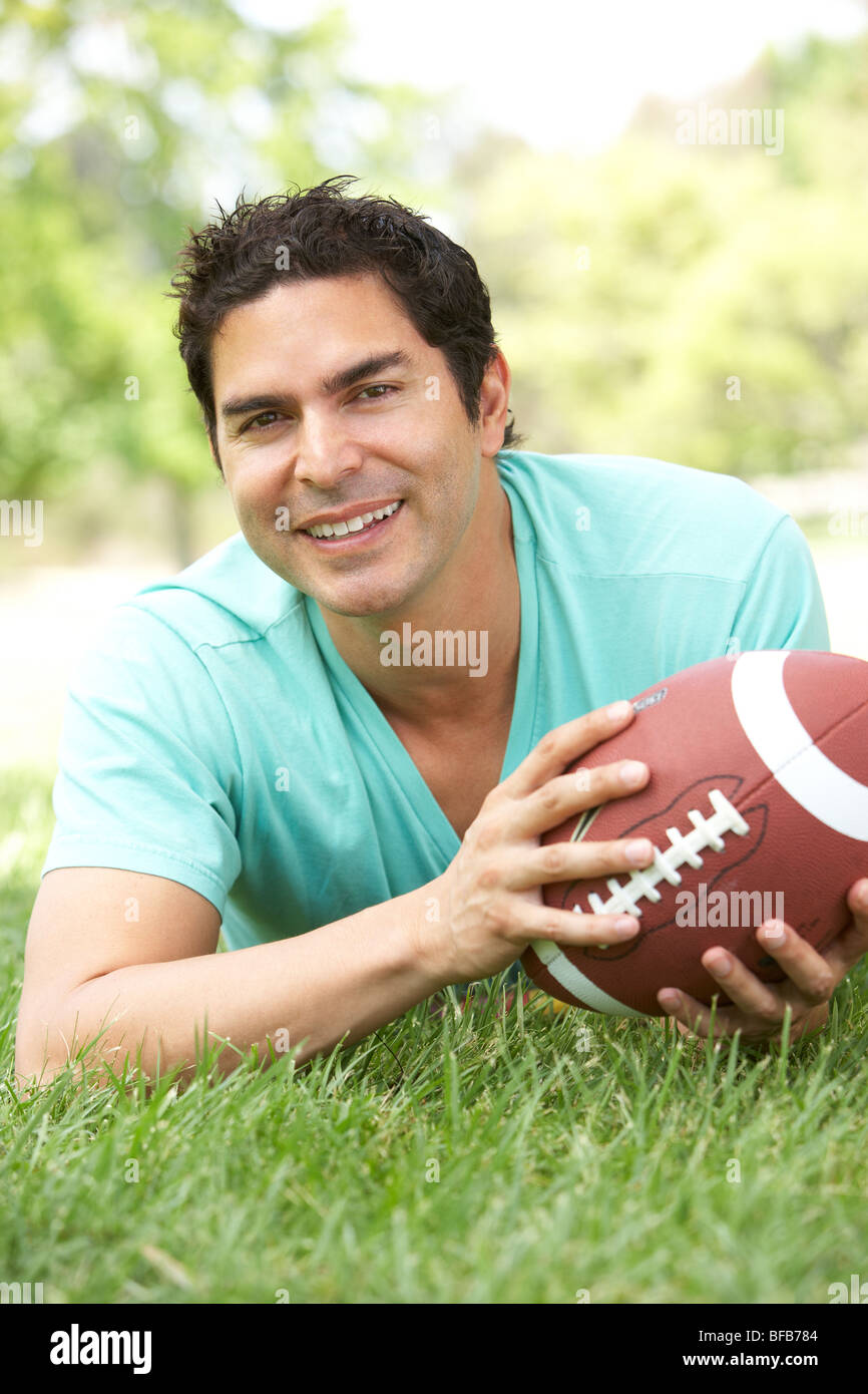 Porträt des jungen Menschen im Park mit American Football Stockfoto