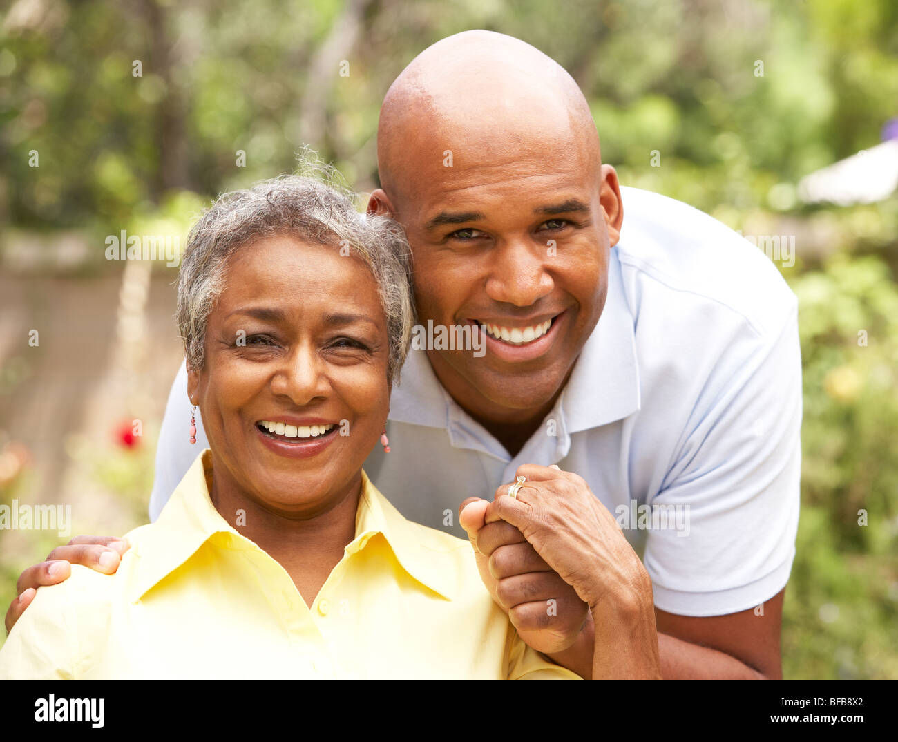 Ältere Frau wird von erwachsenen Sohn umarmt Stockfoto