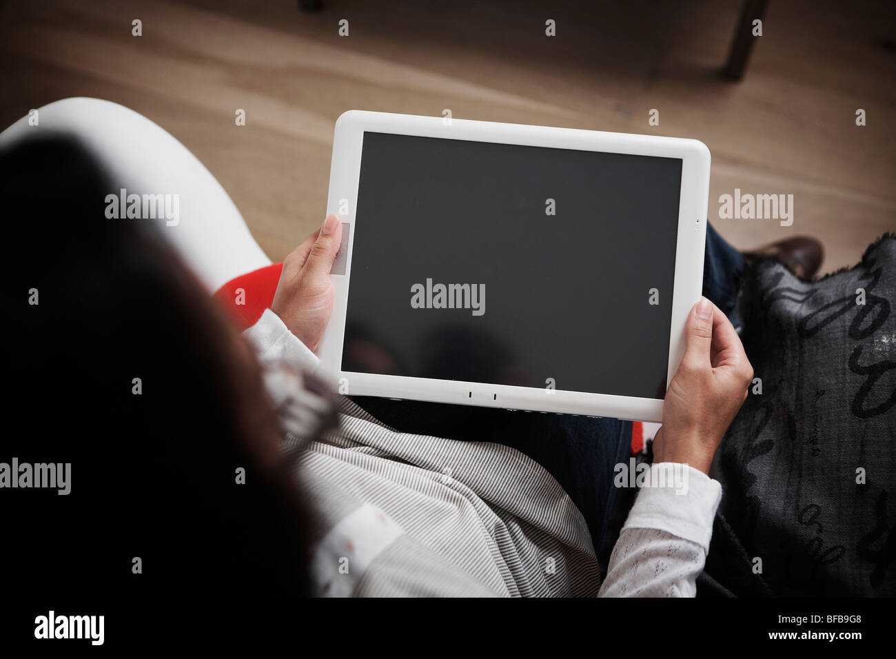 Eine Frau benutzt einen Tablet-PC in einer hellen, gemütlichen Umgebung, Stockfoto