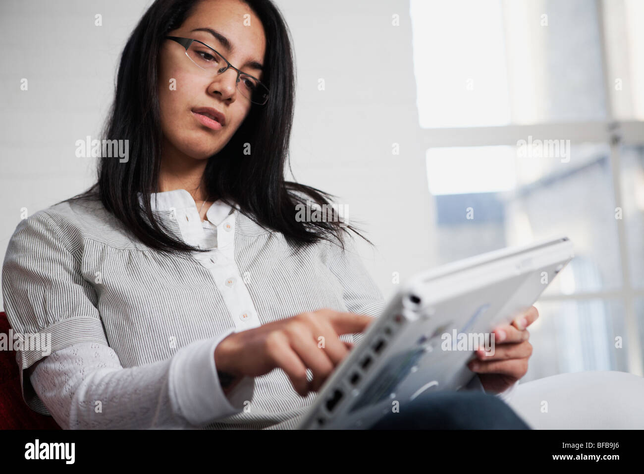 Eine Frau benutzt einen Tablet-PC in einer gemütlichen Umgebung Birght, Stockfoto