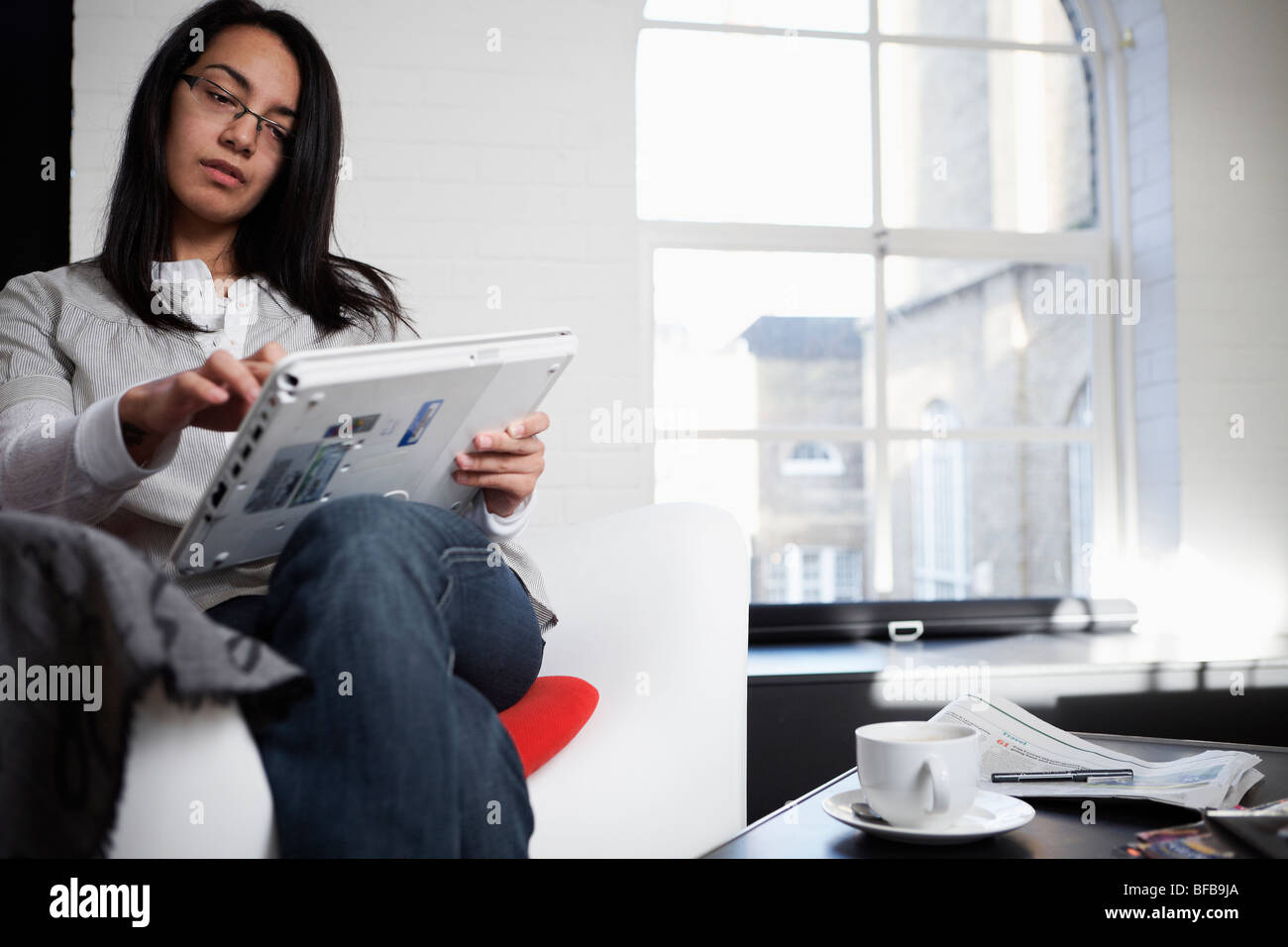 Eine Frau benutzt einen Tablet-PC in einer gemütlichen Umgebung Birght, Stockfoto