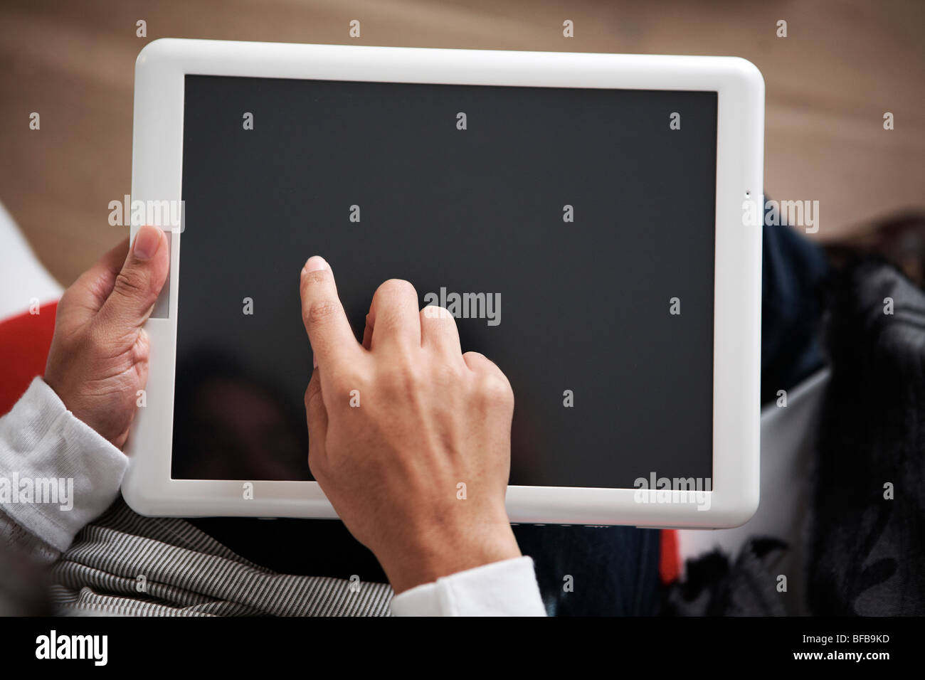 Eine Frau benutzt einen Tablet-PC in einer gemütlichen Umgebung Birght, Stockfoto