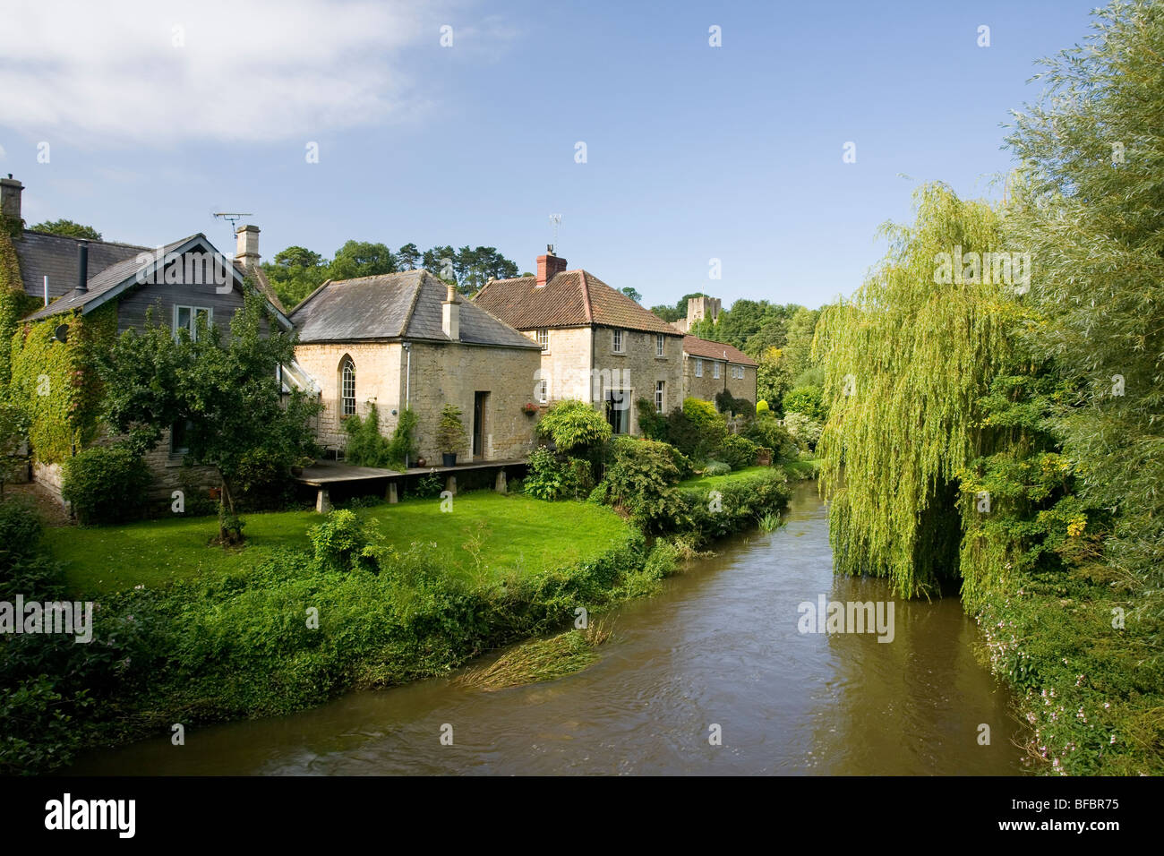 Häuser entlang dem Fluß Frome in Farleigh Hungerford mit Farleigh Castle im Hintergrund Stockfoto