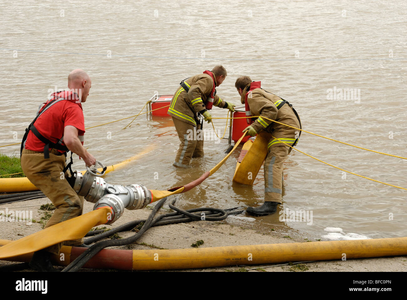 Feuerwehr & Service hochvolumige Pumpen und Schlauch Hochwasser frei aufbauen von hinten einen geschwächten und überquellenden Damm Stockfoto