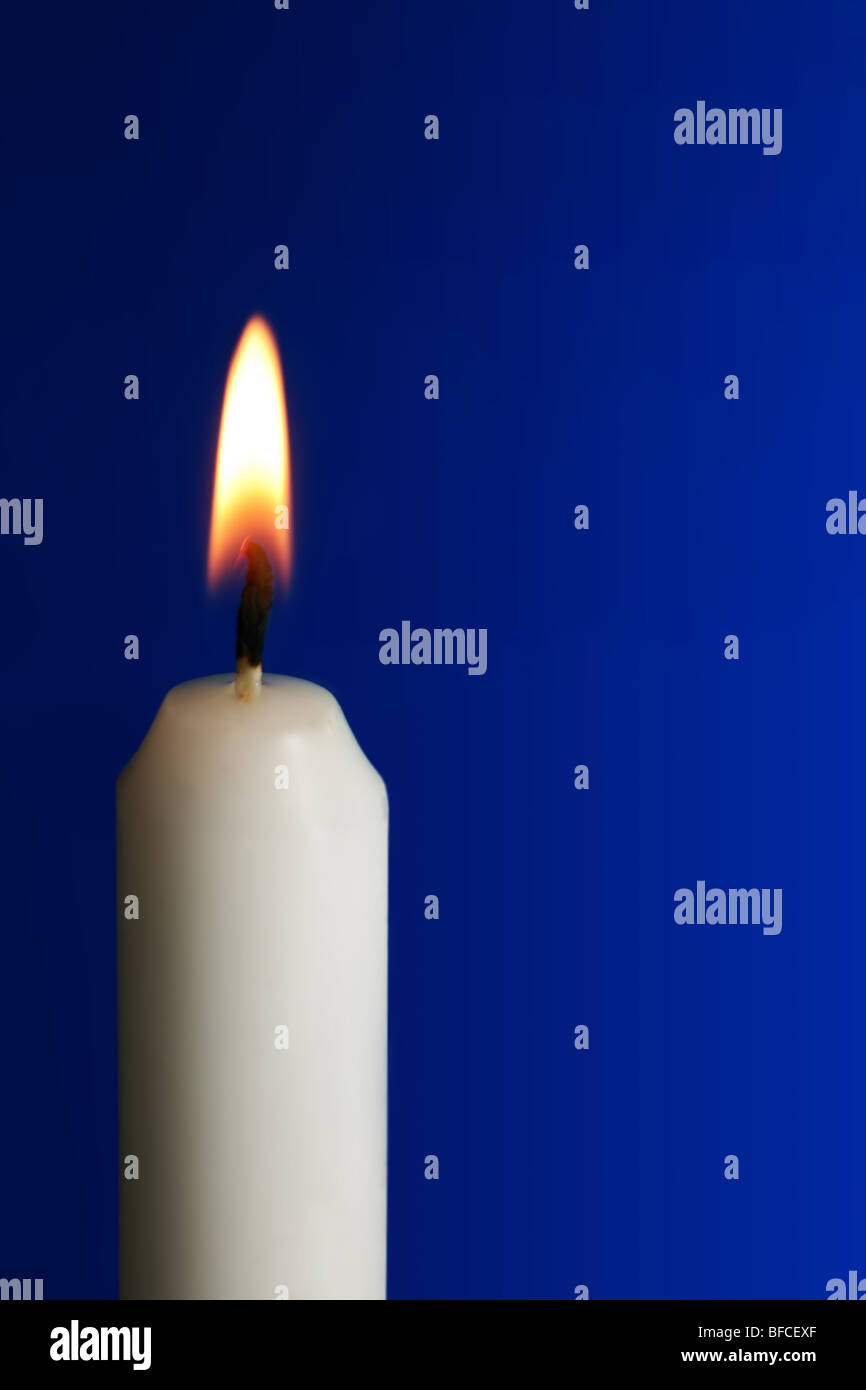 Weißes Wachskerze mit Flamme auf blauem Hintergrund Stockfoto