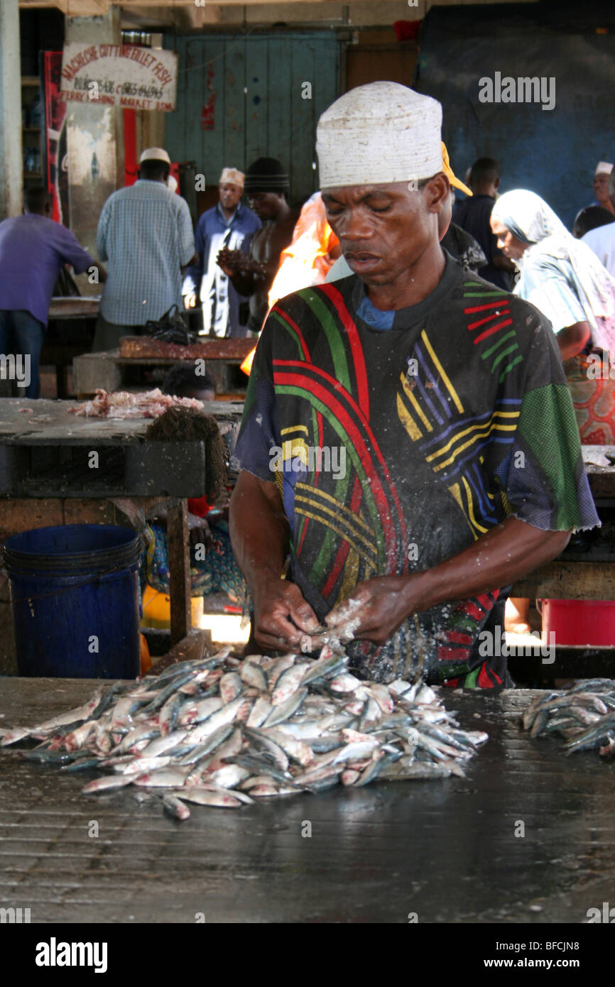 Mann Fischmarkt Entkalkung kleine Fische in Kivukoni, Dar-Es-Salaam, Tansania Stockfoto